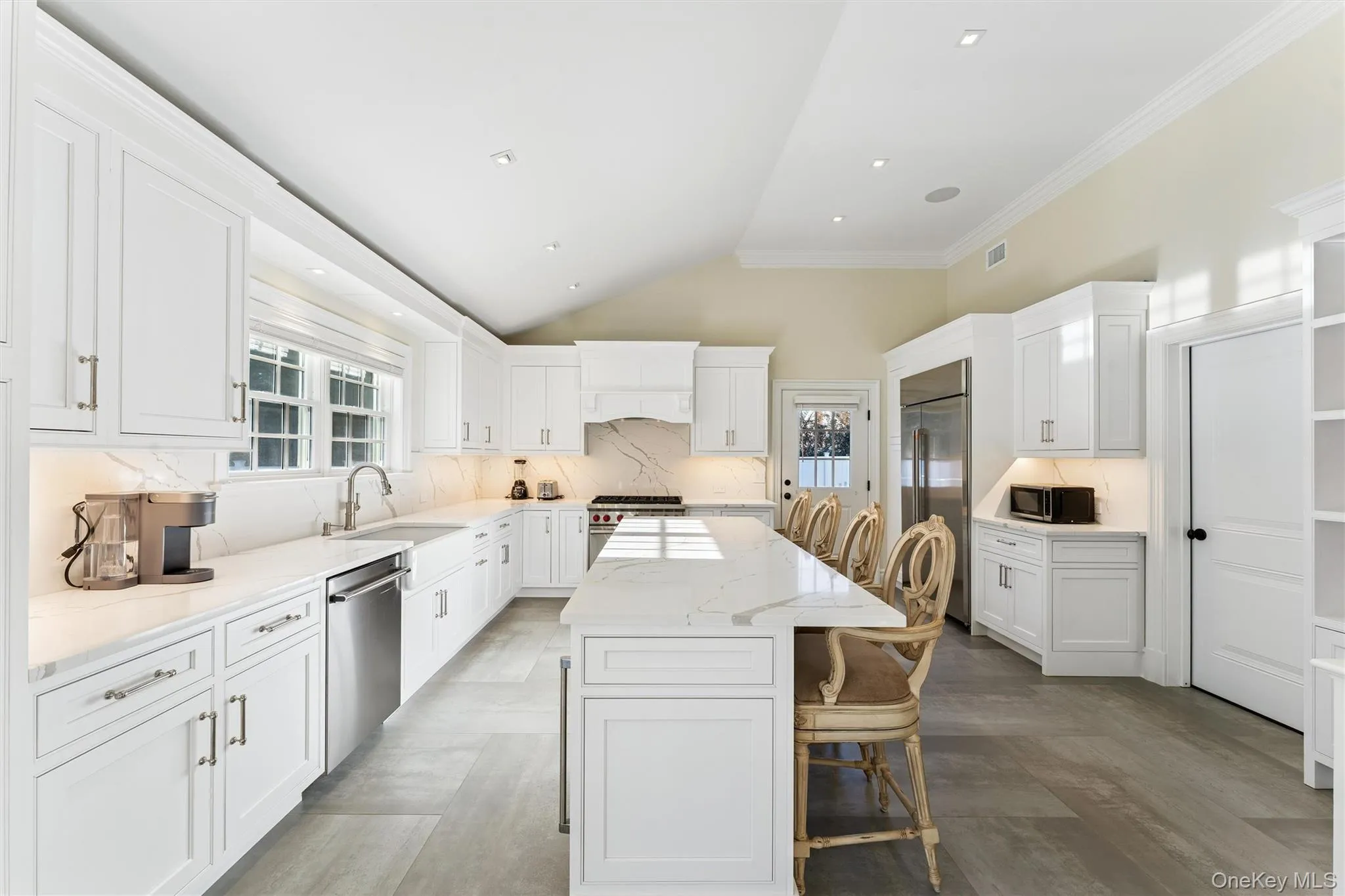Kitchen featuring a kitchen breakfast bar, lofted ceiling, white cabinets, light quartz counters, and a kitchen island. Kitchen featuring a kitchen breakfast bar, lofted ceiling, white cabinets, light quartz counters, and a kitchen island.