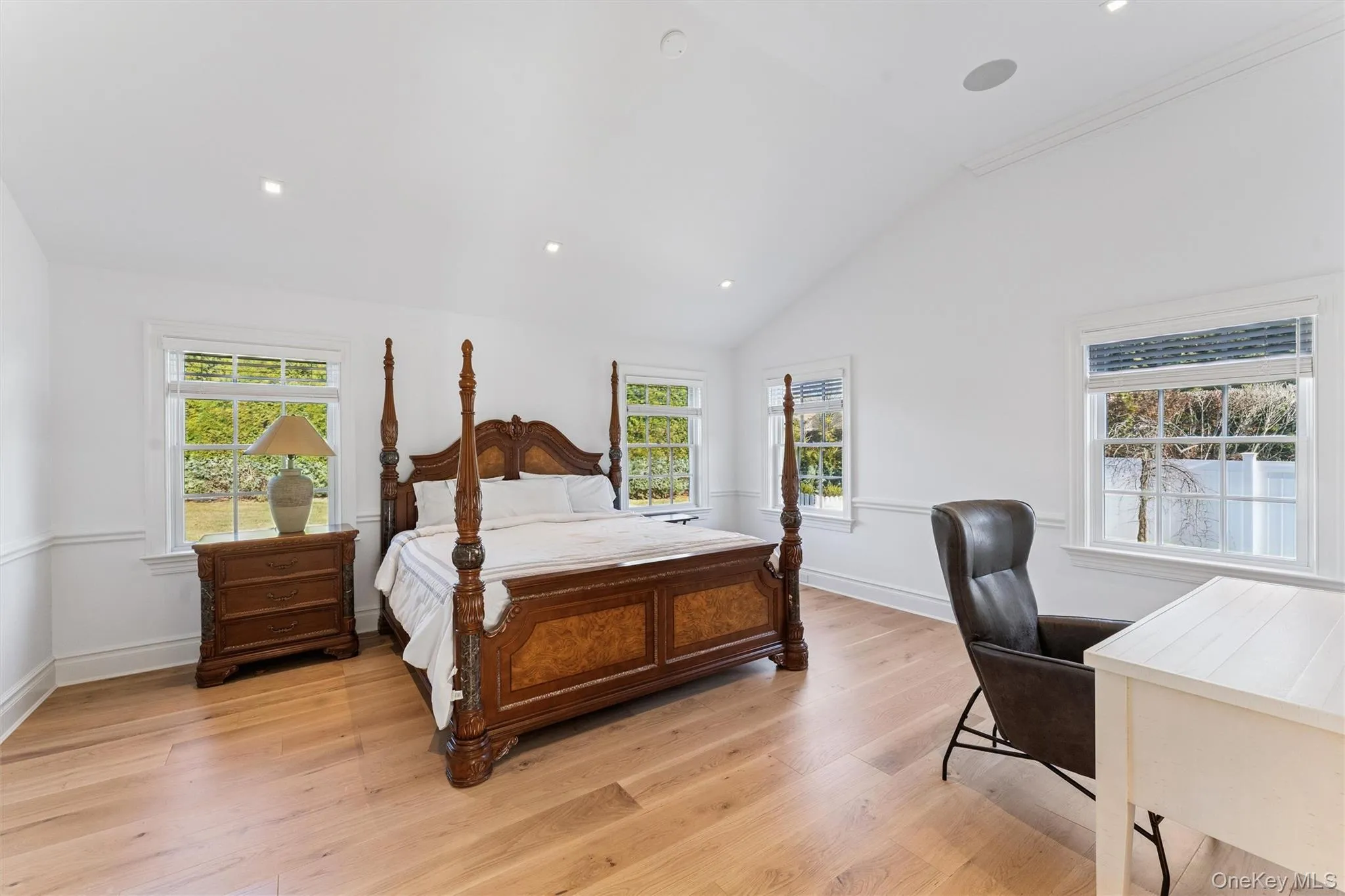 Bedroom featuring lofted ceiling, light wood finished floors, recessed lighting, and multiple windows. Bedroom featuring lofted ceiling, light wood finished floors, recessed lighting, and multiple windows.