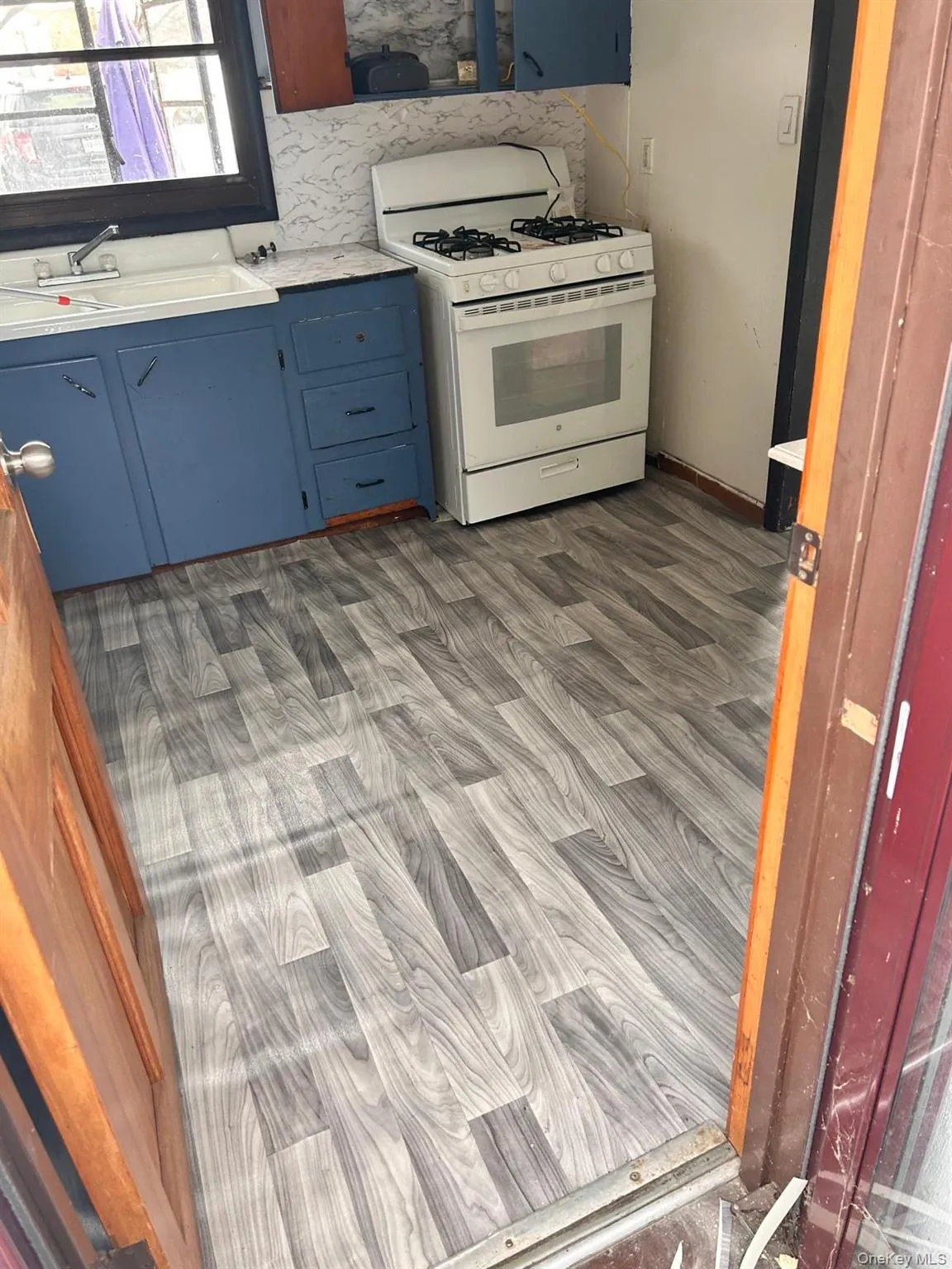 Kitchen with white gas stove, blue cabinets, and light countertops Kitchen with white gas stove, blue cabinets, and light countertops