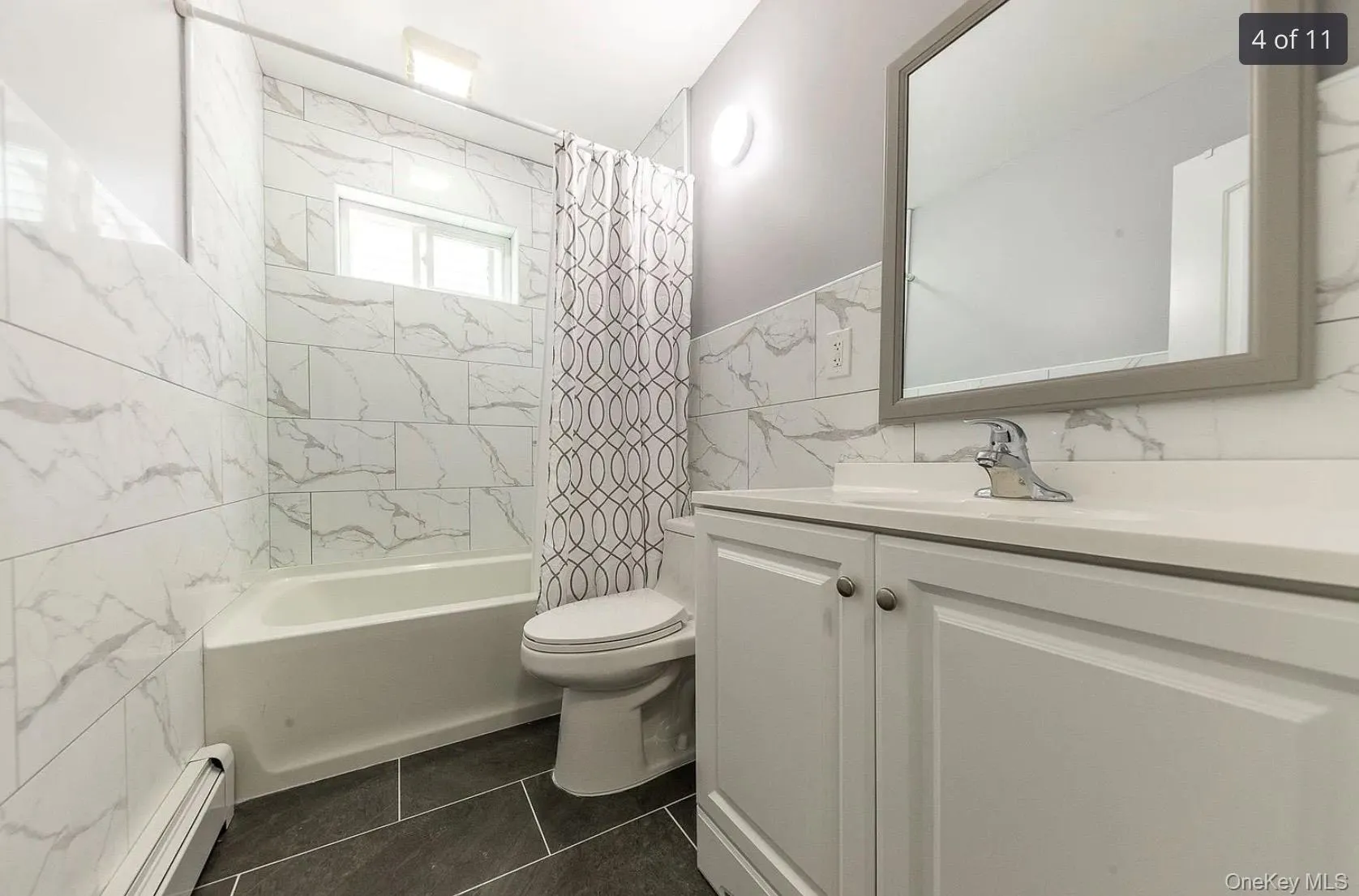 Full bathroom featuring tile walls, a baseboard radiator, shower / bath combination with curtain, and vanity Full bathroom featuring tile walls, a baseboard radiator, shower / bath combination with curtain, and vanity