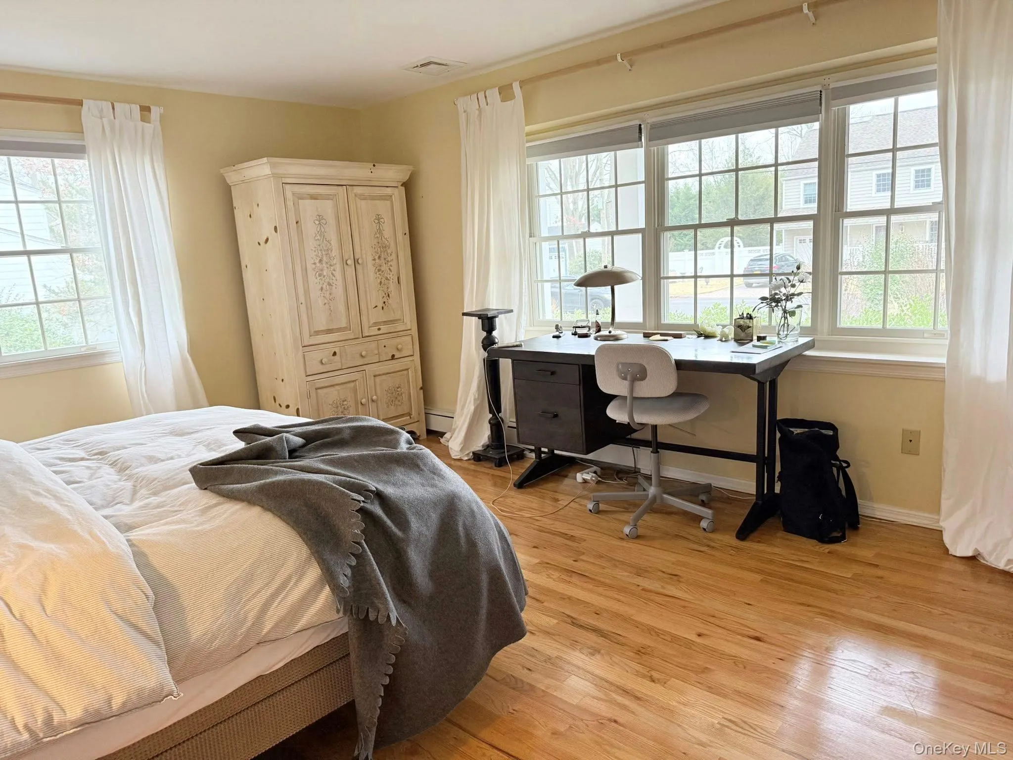 Bedroom with light wood finished floors, multiple windows, and a desk Bedroom with light wood finished floors, multiple windows, and a desk