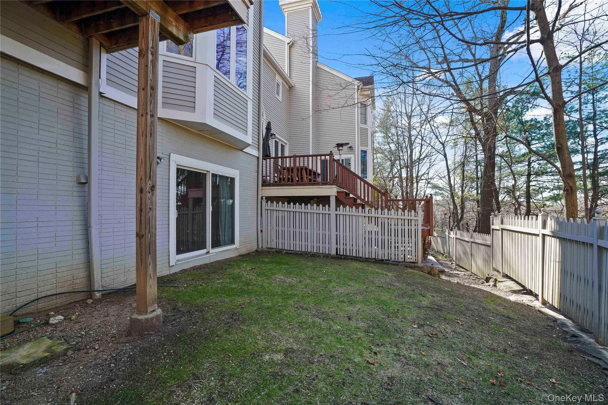 Fenced backyard with a wooden deck and a balcony Fenced backyard with a wooden deck and a balcony