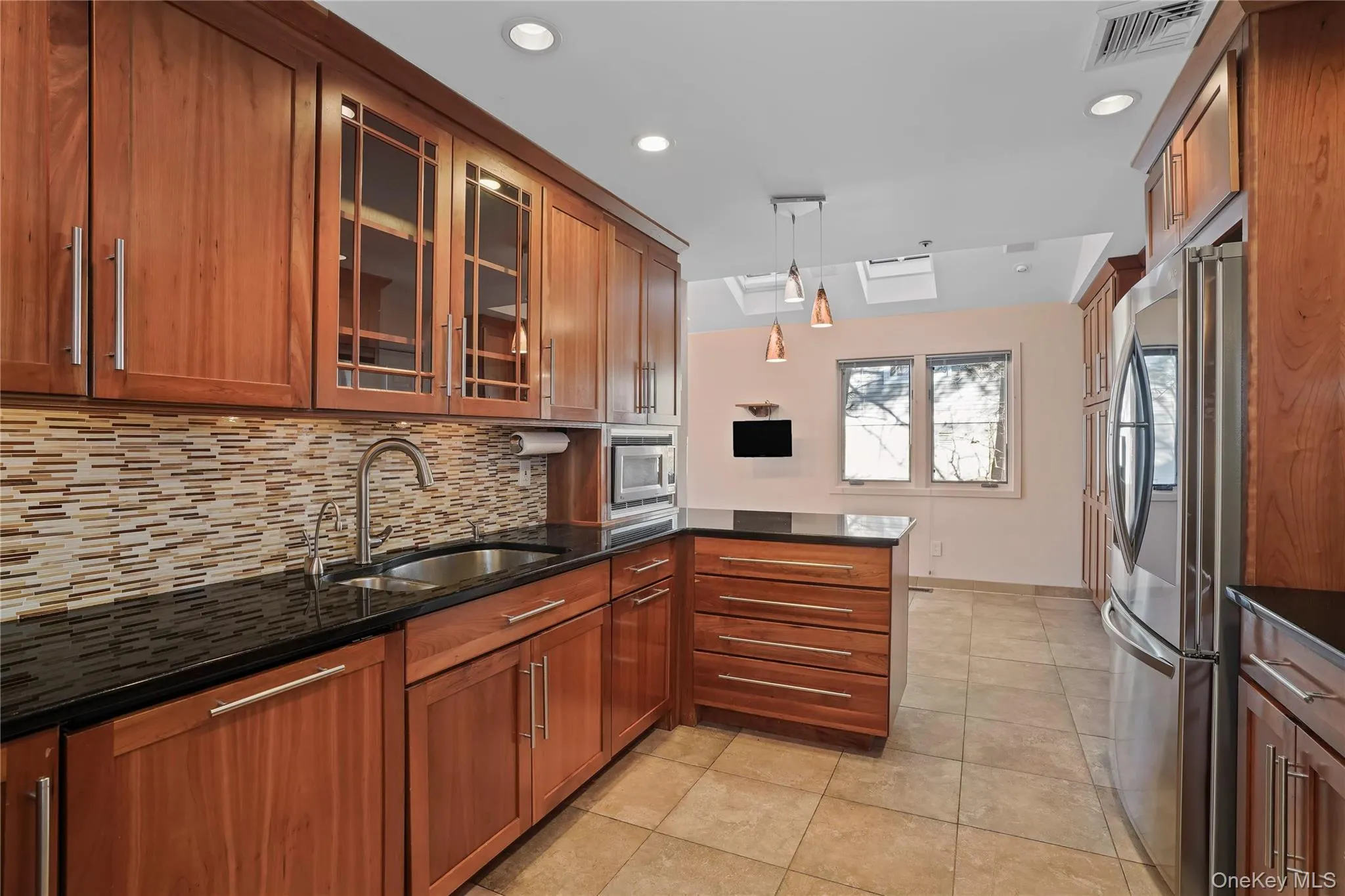 Kitchen featuring glass insert cabinets, brown cabinets, and recessed lighting Kitchen featuring glass insert cabinets, brown cabinets, and recessed lighting