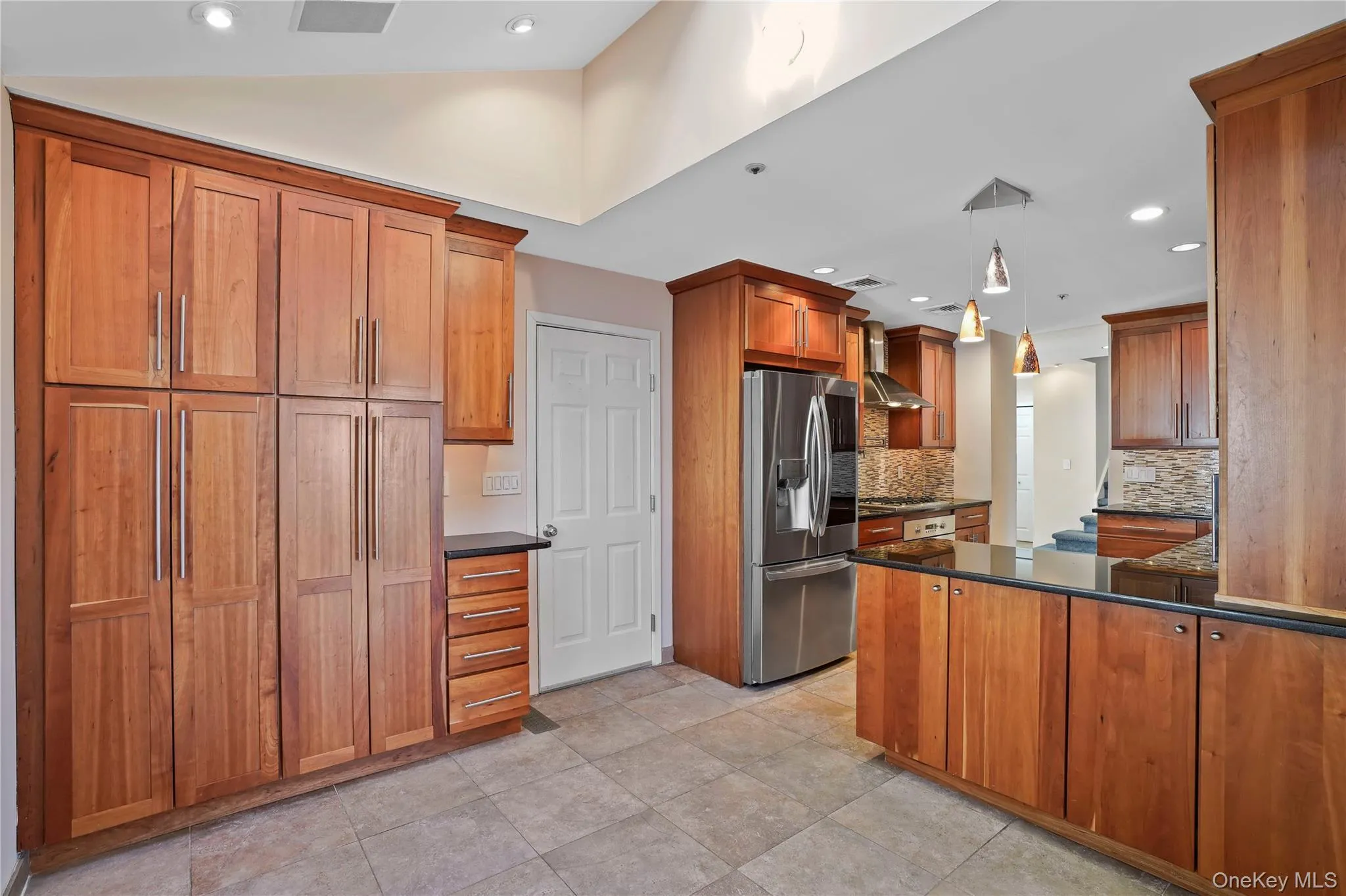 Kitchen with brown cabinets, appliances with stainless steel finishes, pendant lighting, dark stone counters, and recessed lighting Kitchen with brown cabinets, appliances with stainless steel finishes, pendant lighting, dark stone counters, and recessed lighting