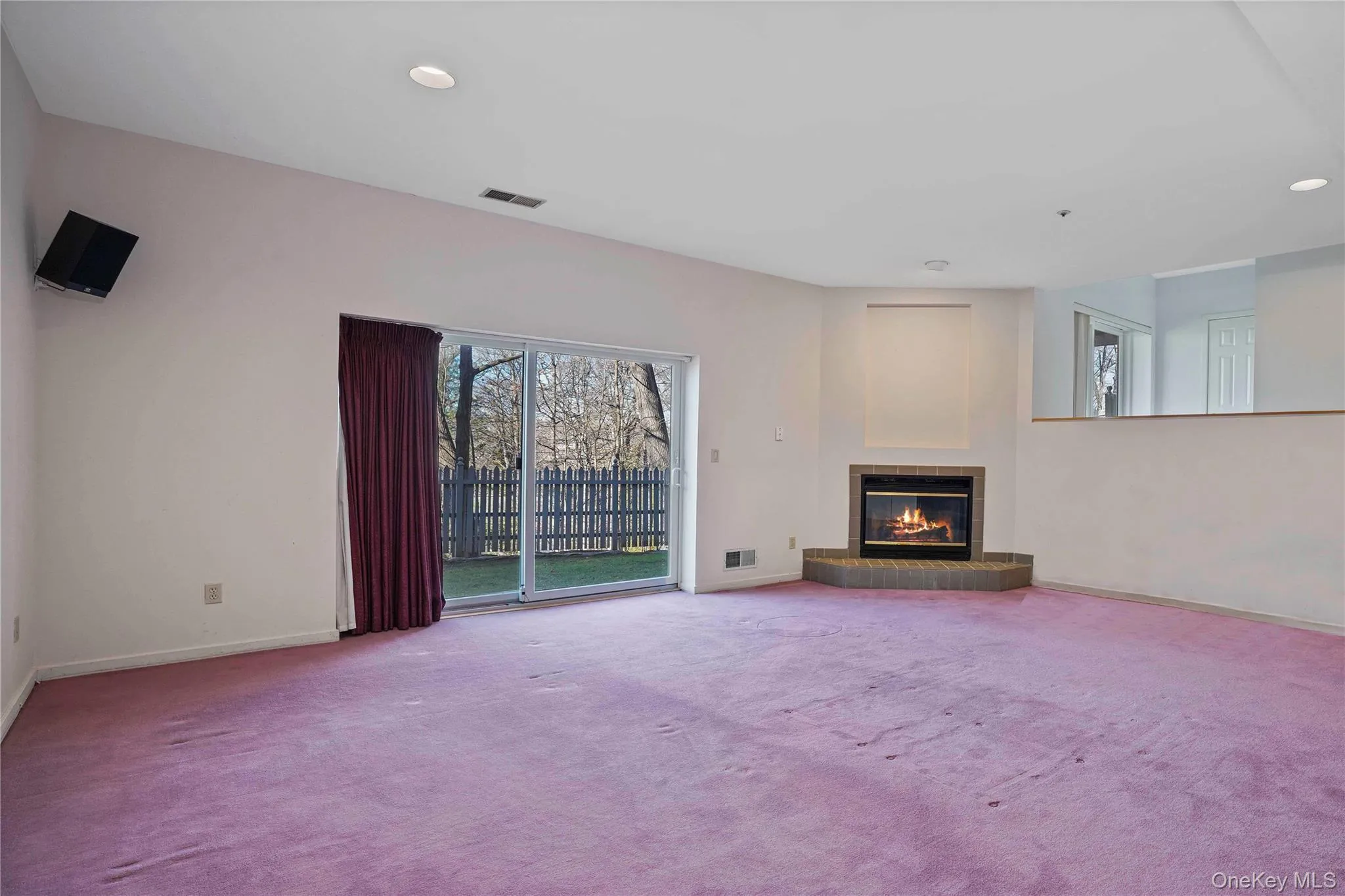 Unfurnished living room with a glass covered fireplace, carpet flooring, and recessed lighting Unfurnished living room with a glass covered fireplace, carpet flooring, and recessed lighting