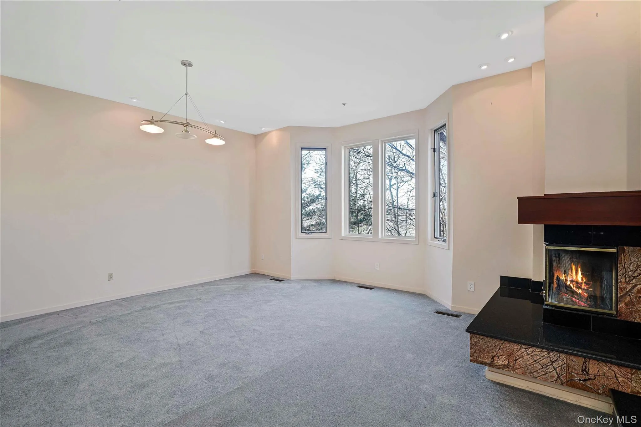 Unfurnished living room featuring a glass covered fireplace, carpet floors, and recessed lighting Unfurnished living room featuring a glass covered fireplace, carpet floors, and recessed lighting