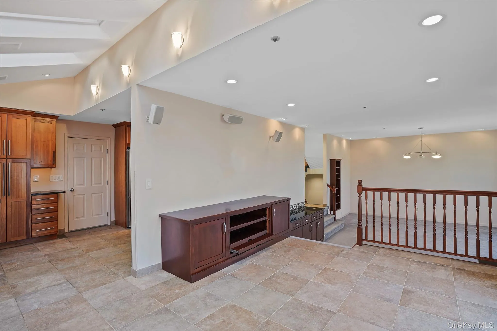 Kitchen with dark countertops, recessed lighting, hanging light fixtures, brown cabinetry, and a chandelier Kitchen with dark countertops, recessed lighting, hanging light fixtures, brown cabinetry, and a chandelier