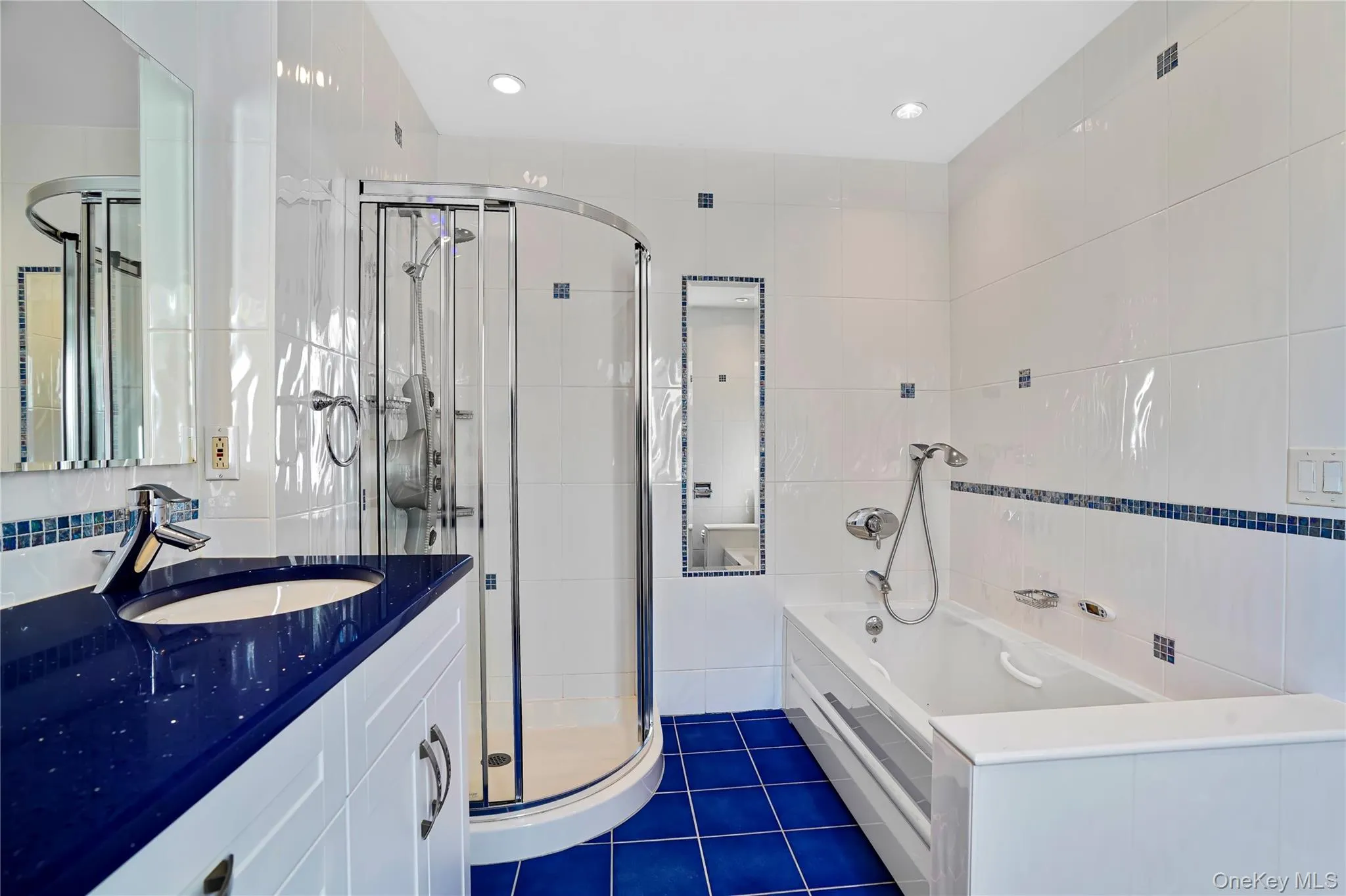 Bathroom with tile walls, a bath, a stall shower, vanity, and dark tile patterned floors Bathroom with tile walls, a bath, a stall shower, vanity, and dark tile patterned floors