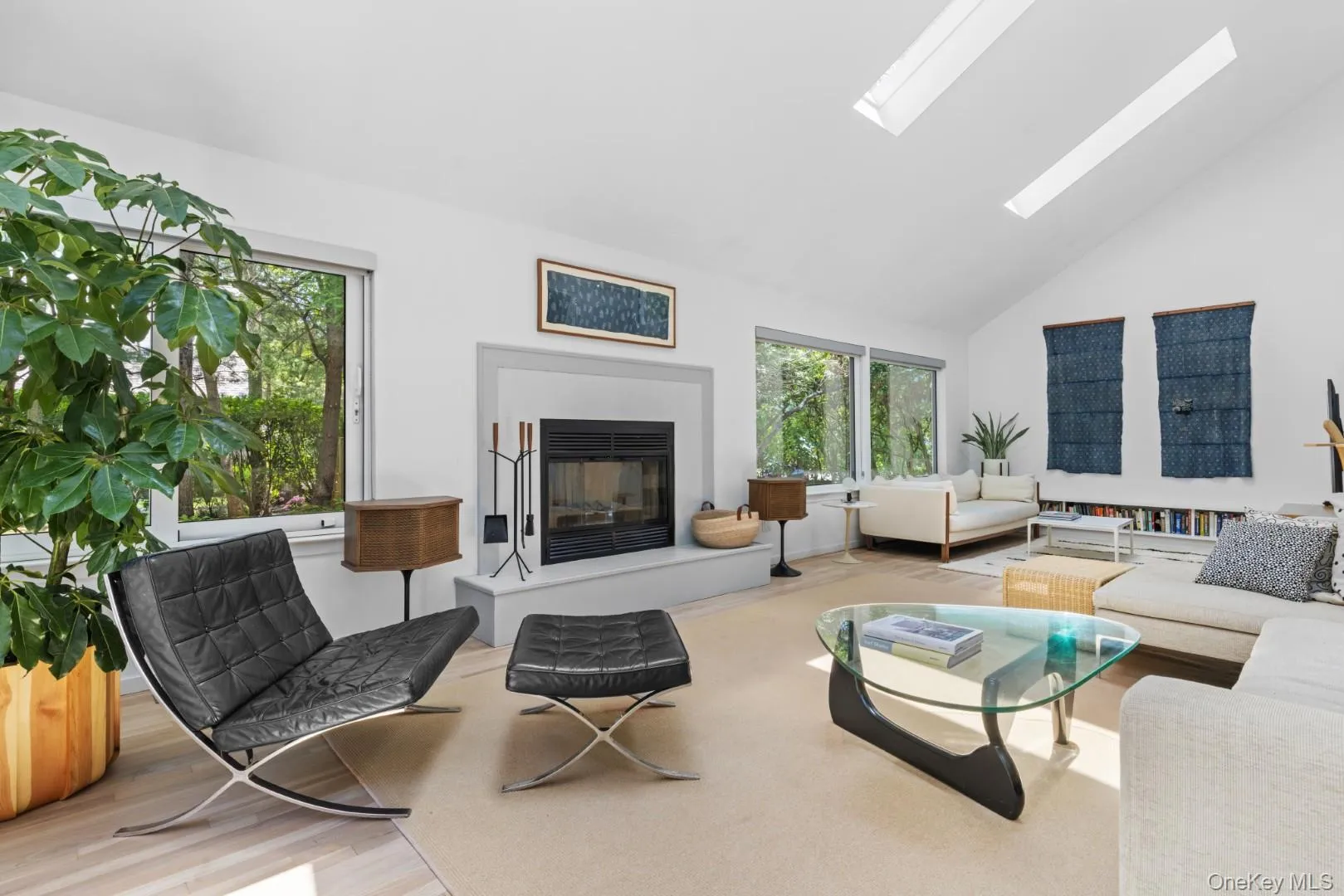 Living area with high vaulted ceiling, a glass covered fireplace, wood finished floors, and a skylight Living area with high vaulted ceiling, a glass covered fireplace, wood finished floors, and a skylight