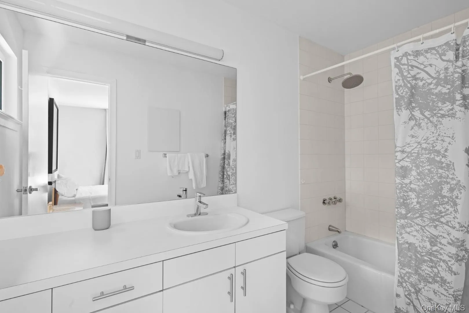 Full bath featuring shower / bath combo with shower curtain, vanity, tile patterned floors, and ensuite bathroom Full bath featuring shower / bath combo with shower curtain, vanity, tile patterned floors, and ensuite bathroom