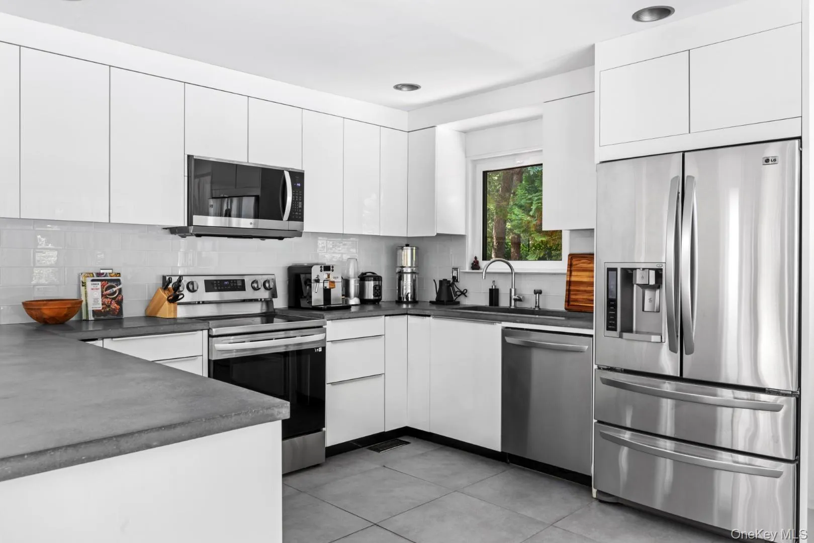 Kitchen with appliances with stainless steel finishes, dark countertops, white cabinetry, and recessed lighting Kitchen with appliances with stainless steel finishes, dark countertops, white cabinetry, and recessed lighting