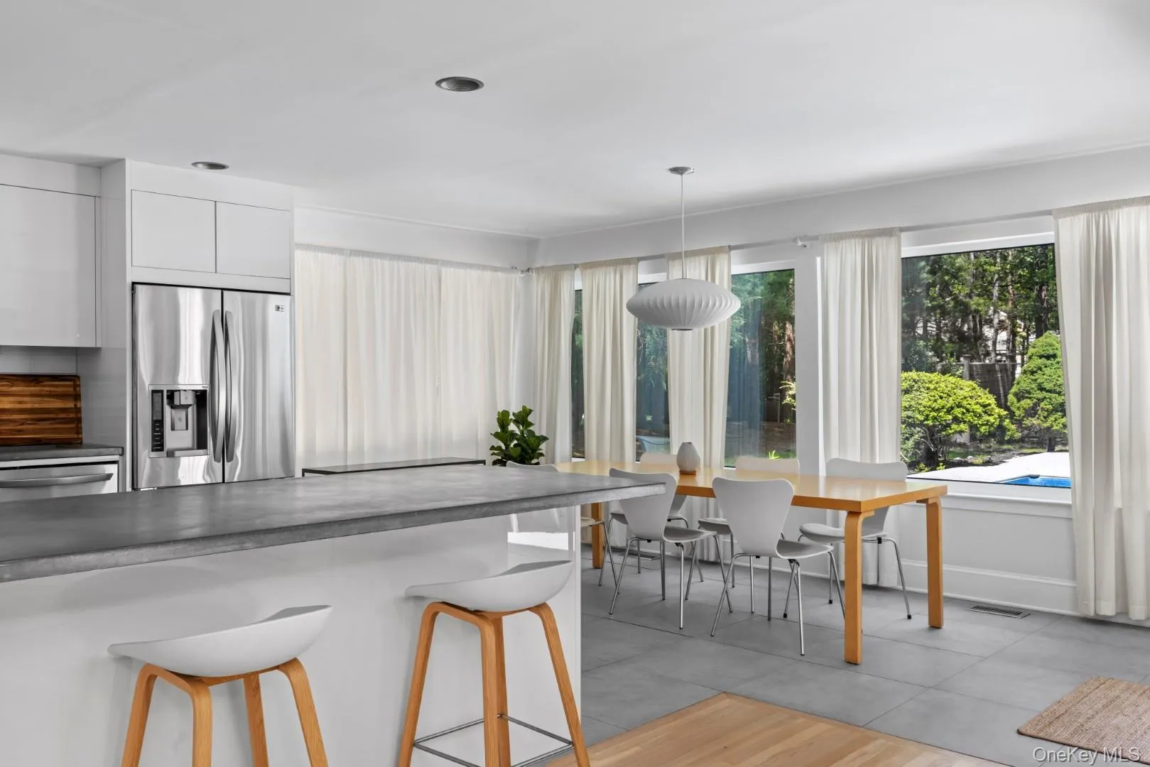 Kitchen with appliances with stainless steel finishes, dark countertops, decorative light fixtures, white cabinetry, and a kitchen bar Kitchen with appliances with stainless steel finishes, dark countertops, decorative light fixtures, white cabinetry, and a kitchen bar