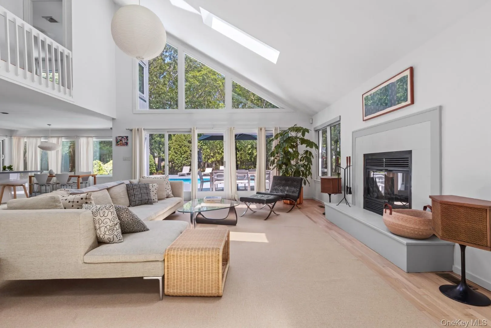 Living area featuring high vaulted ceiling, a skylight, wood finished floors, and a glass covered fireplace Living area featuring high vaulted ceiling, a skylight, wood finished floors, and a glass covered fireplace