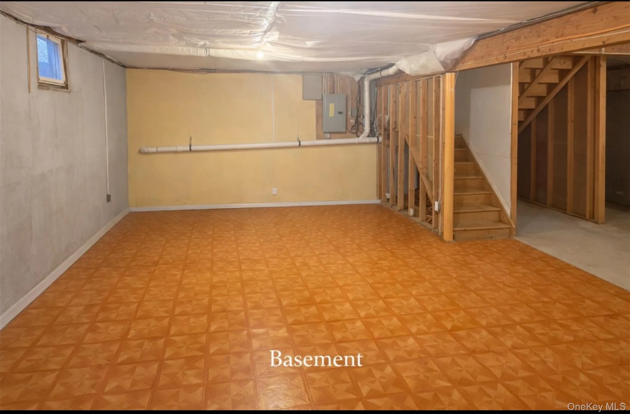 Basement featuring stairway, light flooring, and electric panel Basement featuring stairway, light flooring, and electric panel