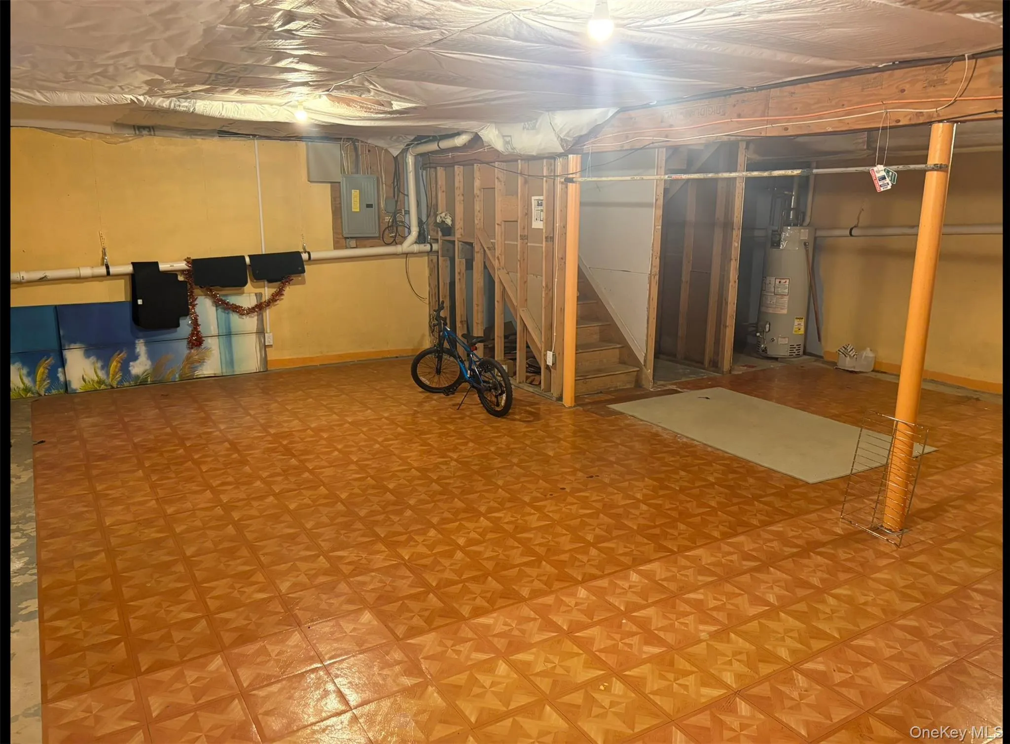 Unfinished below grade area with stairway, tile patterned floors, electric panel, and gas water heater Unfinished below grade area with stairway, tile patterned floors, electric panel, and gas water heater