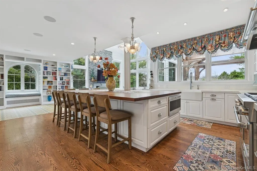Kitchen featuring butcher block counters, a breakfast bar, built in features, pendant lighting, and appliances with stainless steel finishes Kitchen featuring butcher block counters, a breakfast bar, built in features, pendant lighting, and appliances with stainless steel finishes