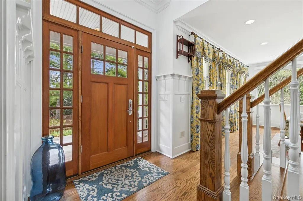 Foyer entrance with healthy amount of natural light, stairs, wainscoting, a decorative wall, and ornamental molding Foyer entrance with healthy amount of natural light, stairs, wainscoting, a decorative wall, and ornamental molding