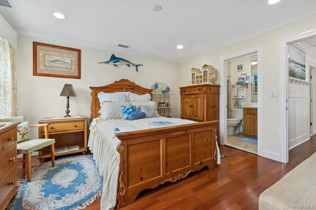 Bedroom featuring dark wood-style floors, crown molding, ensuite bathroom, and recessed lighting Bedroom featuring dark wood-style floors, crown molding, ensuite bathroom, and recessed lighting