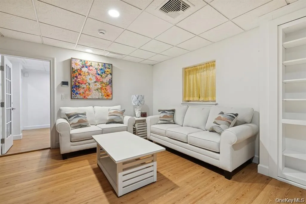 Living area with a paneled ceiling, light wood-type flooring, and built in shelves Living area with a paneled ceiling, light wood-type flooring, and built in shelves