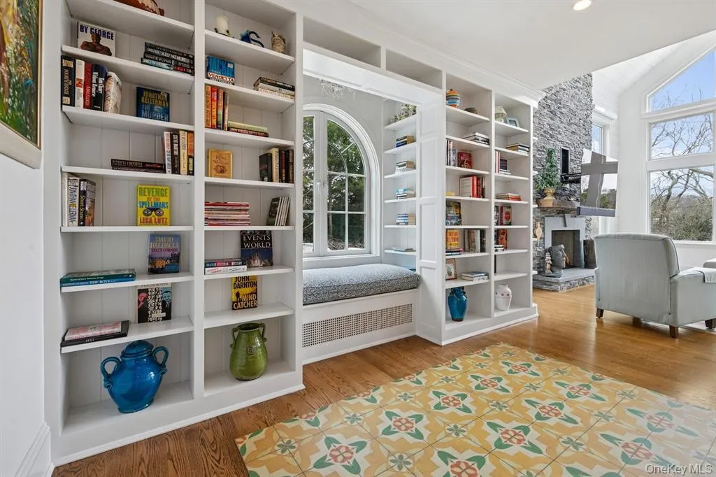 Sitting room with light wood-type flooring, a fireplace, vaulted ceiling, and built in shelves Sitting room with light wood-type flooring, a fireplace, vaulted ceiling, and built in shelves