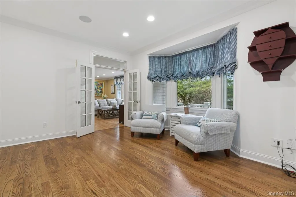 Living area featuring french doors, wood finished floors, ornamental molding, recessed lighting, and healthy amount of natural light Living area featuring french doors, wood finished floors, ornamental molding, recessed lighting, and healthy amount of natural light