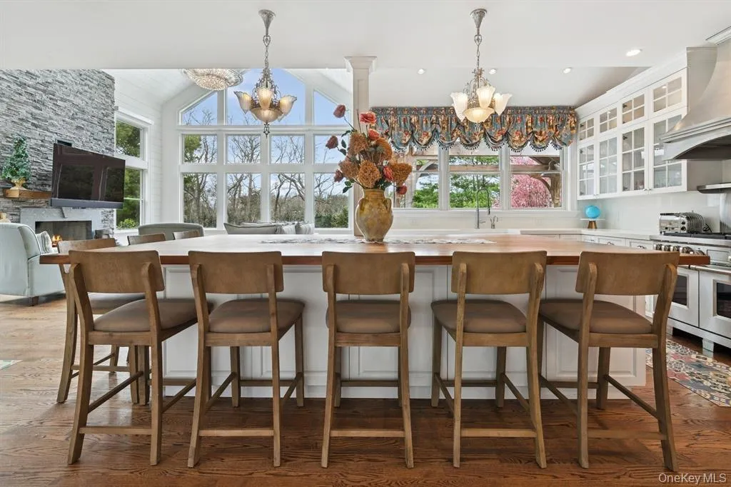 Kitchen with glass insert cabinets, wood counters, pendant lighting, a chandelier, and white cabinets Kitchen with glass insert cabinets, wood counters, pendant lighting, a chandelier, and white cabinets