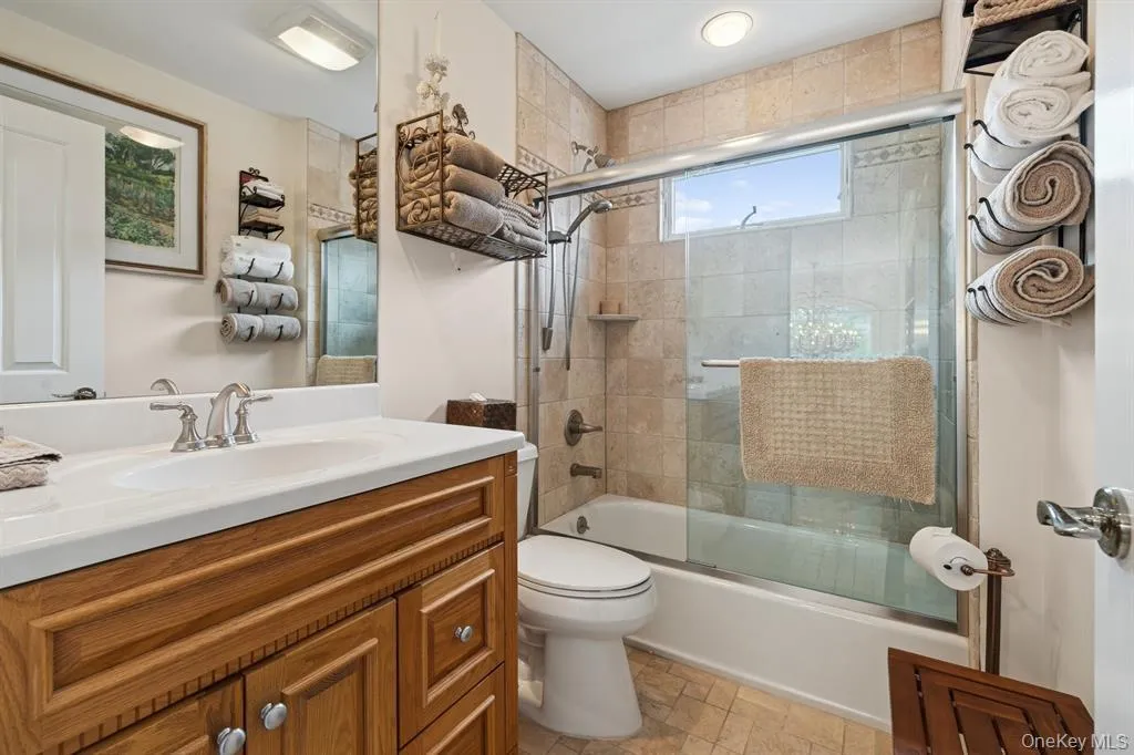 Bathroom with combined bath / shower with glass door, vanity, and stone finish floors Bathroom with combined bath / shower with glass door, vanity, and stone finish floors