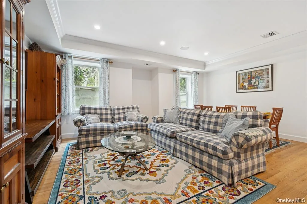 Living area with ornamental molding, plenty of natural light, light wood-style flooring, recessed lighting, and a raised ceiling Living area with ornamental molding, plenty of natural light, light wood-style flooring, recessed lighting, and a raised ceiling