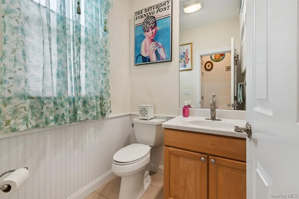 Bathroom with vanity, a wainscoted wall, and light tile patterned flooring Bathroom with vanity, a wainscoted wall, and light tile patterned flooring