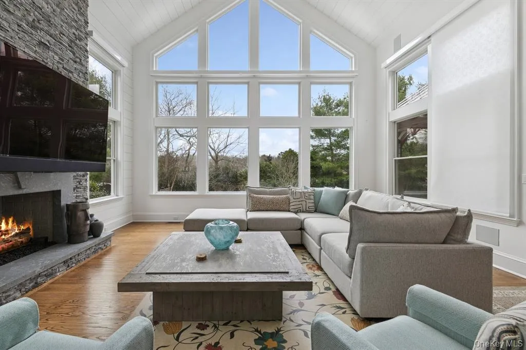 Living room featuring wood finished floors, a fireplace, and high vaulted ceiling Living room featuring wood finished floors, a fireplace, and high vaulted ceiling