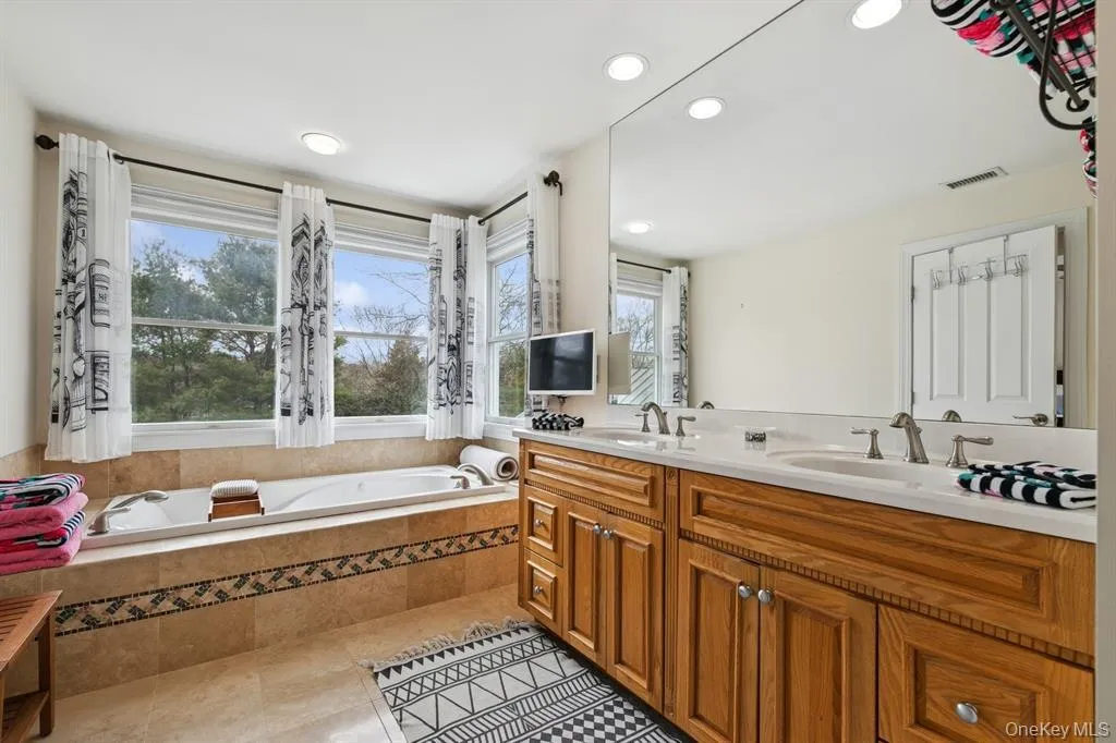 Bathroom with double vanity, a garden tub, recessed lighting, and light tile patterned floors Bathroom with double vanity, a garden tub, recessed lighting, and light tile patterned floors