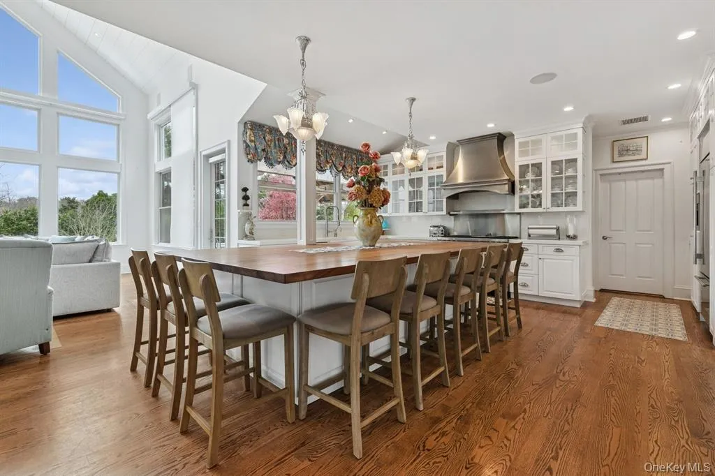 Kitchen with butcher block counters, a kitchen breakfast bar, glass insert cabinets, white cabinets, and pendant lighting Kitchen with butcher block counters, a kitchen breakfast bar, glass insert cabinets, white cabinets, and pendant lighting