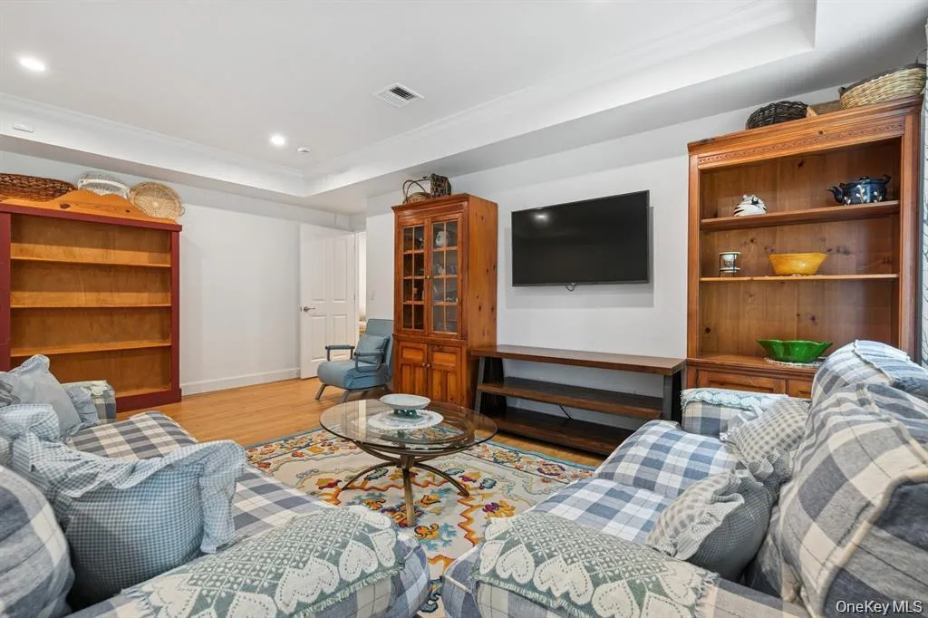 Living room with a raised ceiling, light wood finished floors, recessed lighting, and crown molding Living room with a raised ceiling, light wood finished floors, recessed lighting, and crown molding