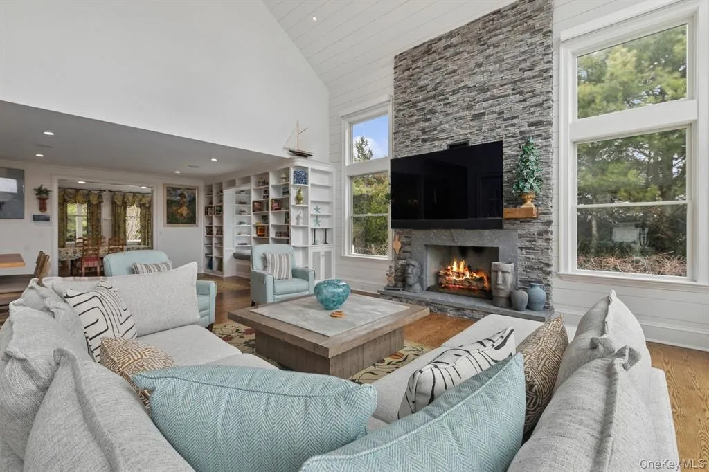 Living room with high vaulted ceiling, wood finished floors, and a fireplace Living room with high vaulted ceiling, wood finished floors, and a fireplace