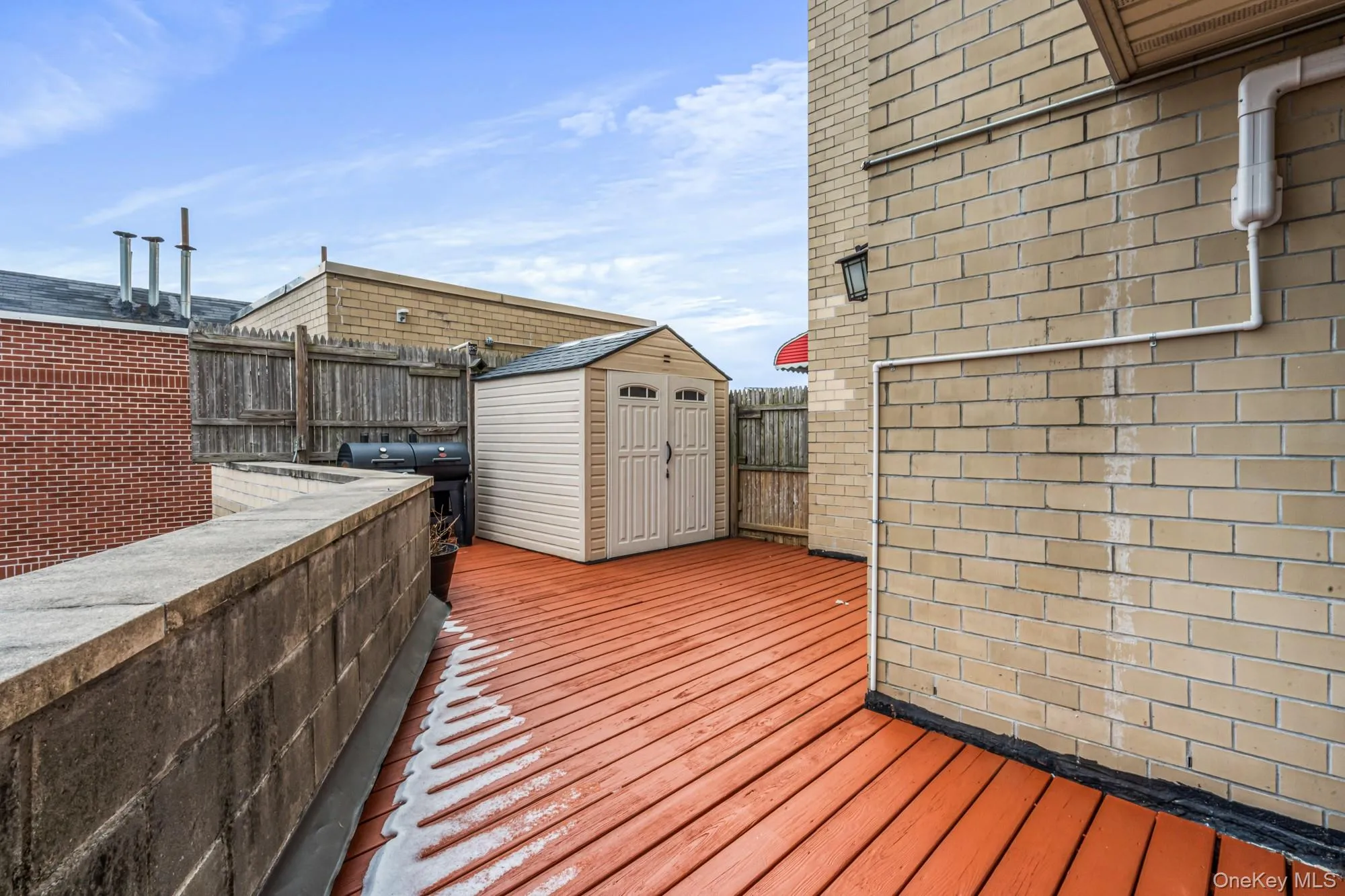 Wooden terrace featuring a fenced backyard and a storage unit Wooden terrace featuring a fenced backyard and a storage unit