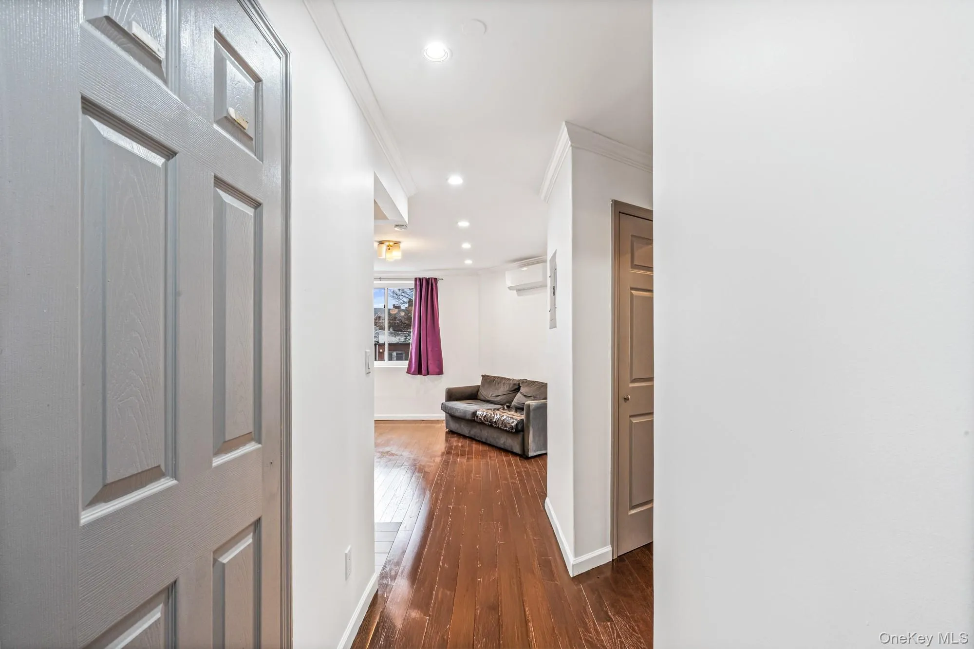 Corridor featuring ornamental molding, recessed lighting, dark wood-style floors, and an AC wall unit Corridor featuring ornamental molding, recessed lighting, dark wood-style floors, and an AC wall unit