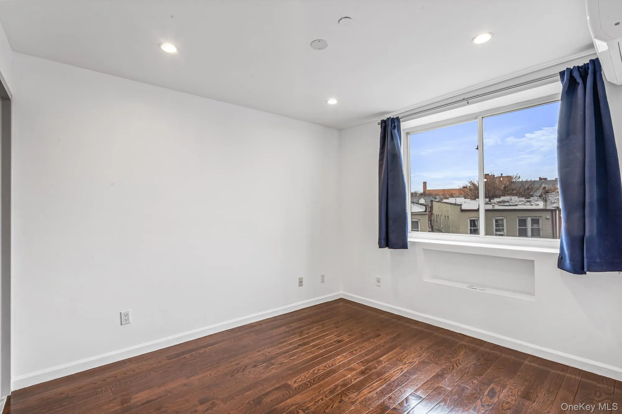 Spare room featuring dark wood-style floors, a wall unit AC, and recessed lighting Spare room featuring dark wood-style floors, a wall unit AC, and recessed lighting