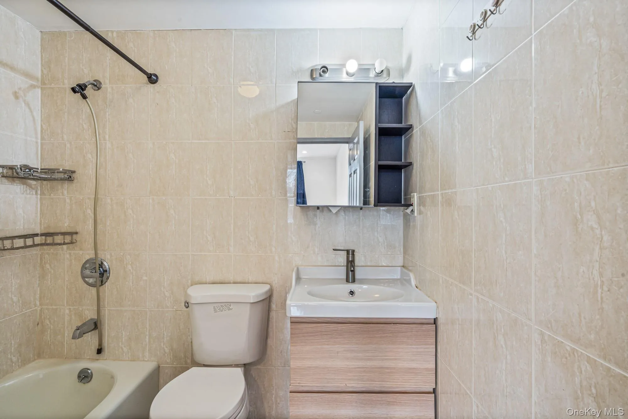 Full bathroom featuring vanity, bathtub / shower combination, and tile walls Full bathroom featuring vanity, bathtub / shower combination, and tile walls