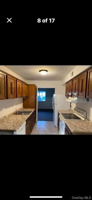 Kitchen featuring brown cabinetry, electric stove, light countertops, and light tile patterned floors Kitchen featuring brown cabinetry, electric stove, light countertops, and light tile patterned floors