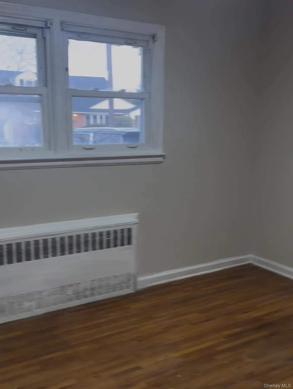 Spare room with radiator heating unit and dark wood-style floors Spare room with radiator heating unit and dark wood-style floors