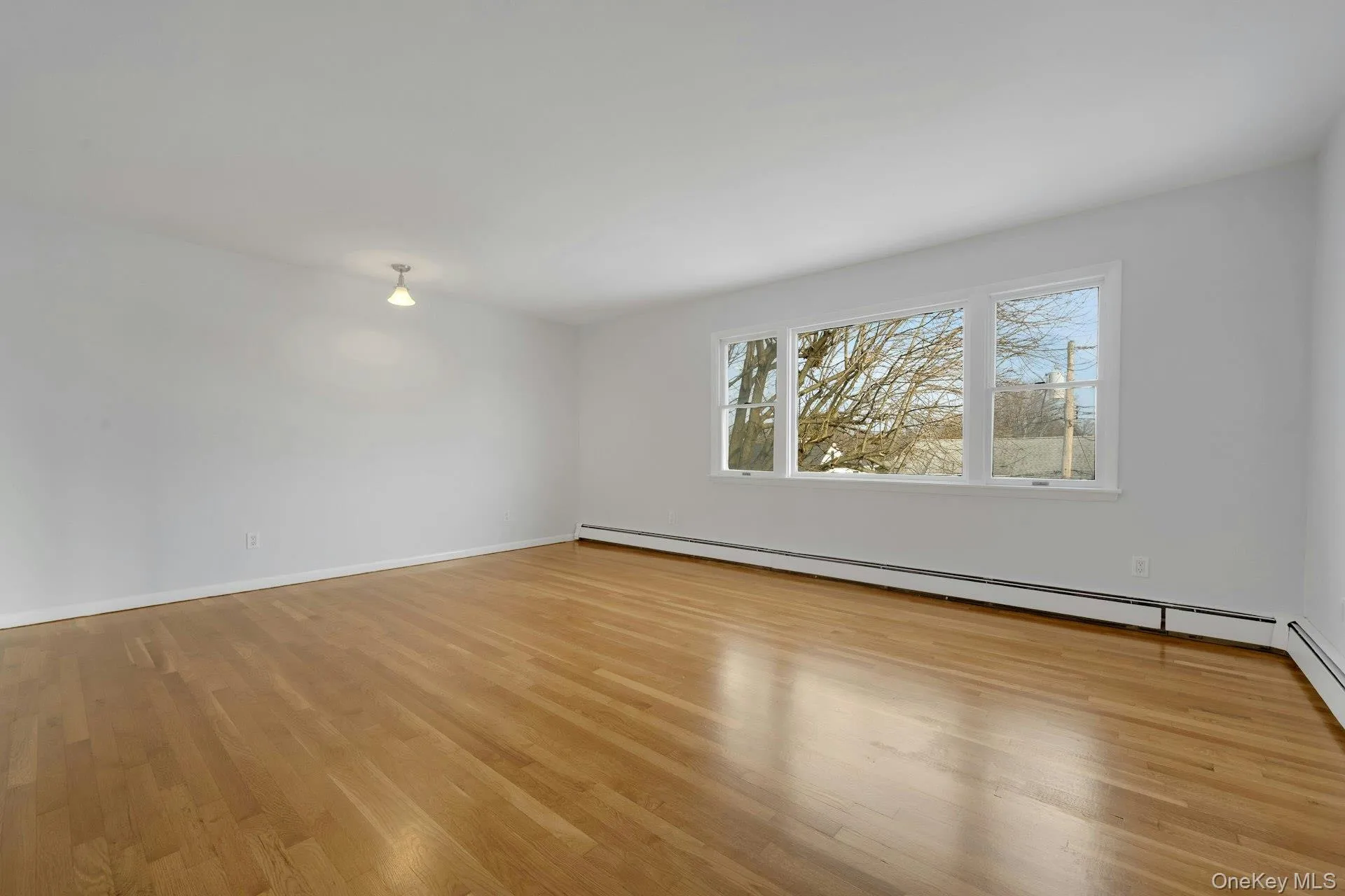 Spare room with baseboard heating and light wood-style floors Spare room with baseboard heating and light wood-style floors
