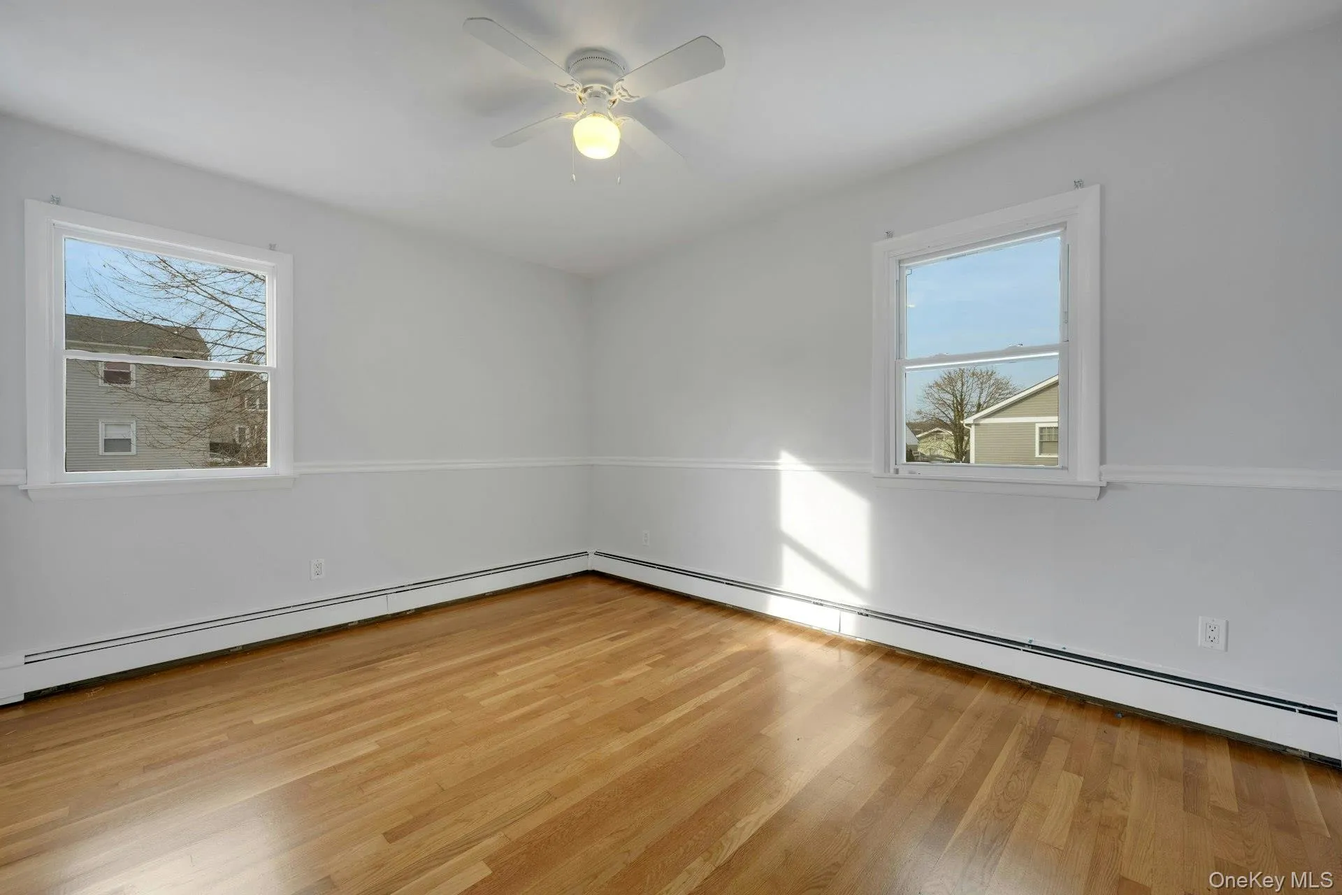 Spare room with baseboard heating, light wood finished floors, and plenty of natural light Spare room with baseboard heating, light wood finished floors, and plenty of natural light