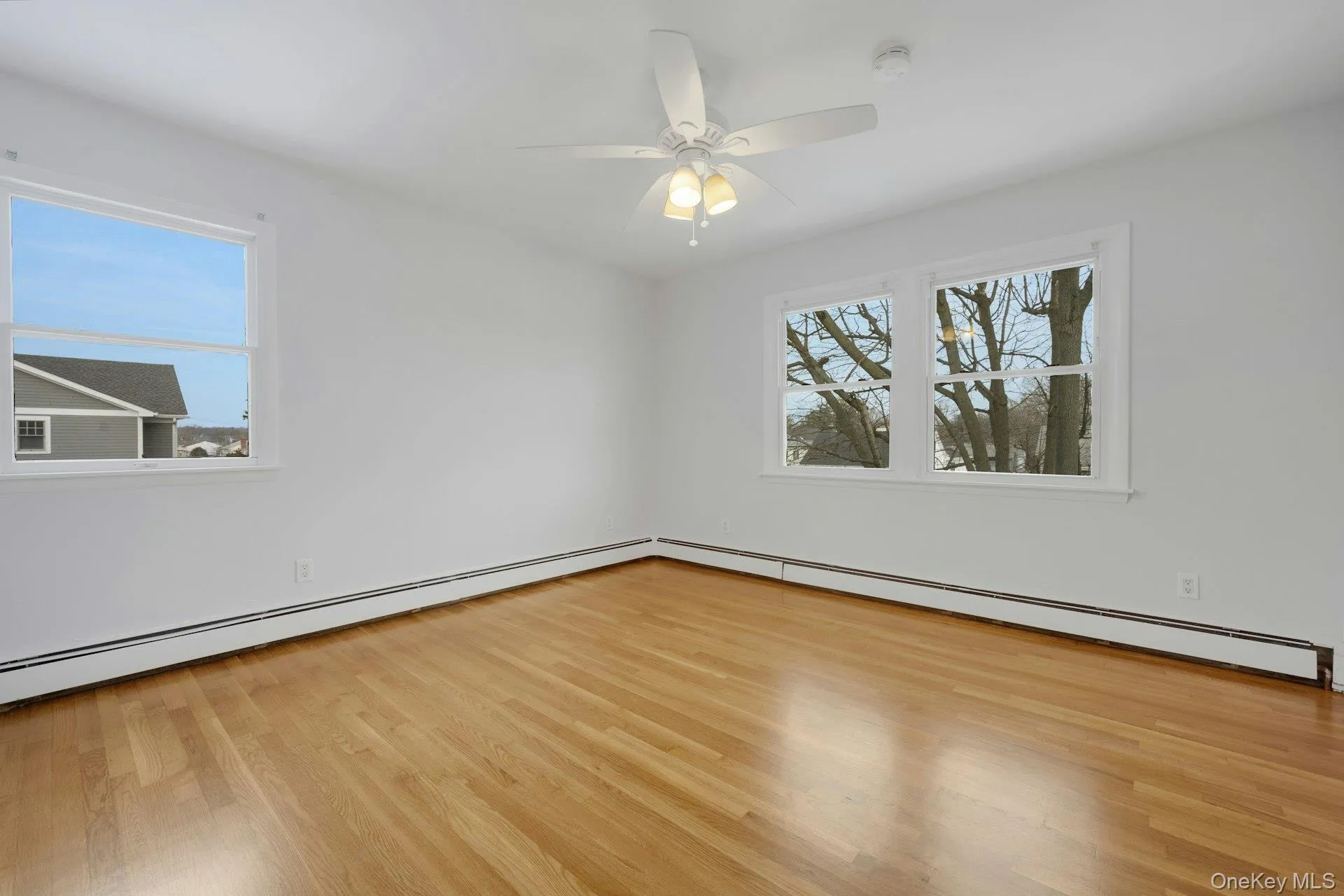 Unfurnished room with light wood-type flooring, baseboard heating, and a ceiling fan Unfurnished room with light wood-type flooring, baseboard heating, and a ceiling fan