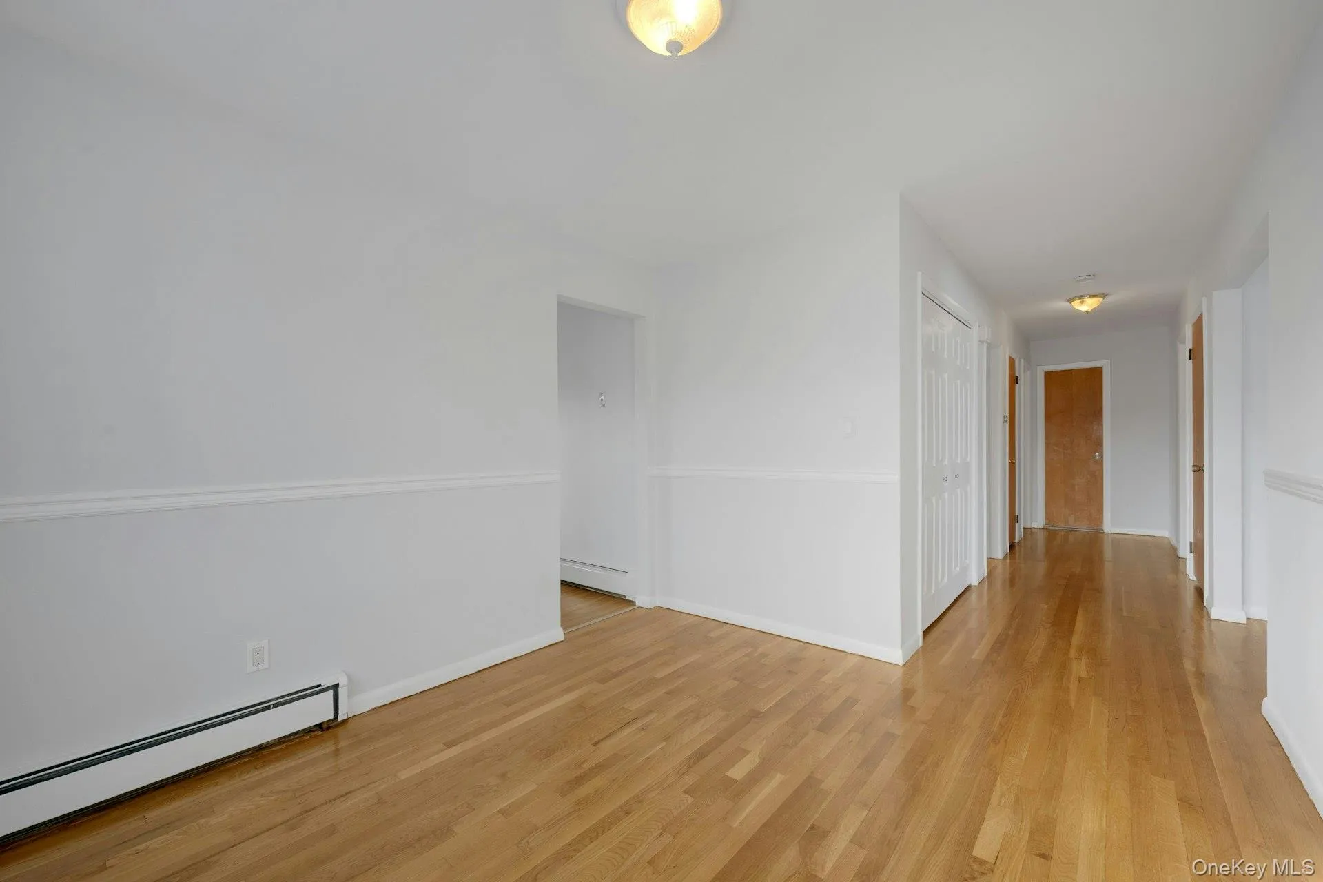 Unfurnished room featuring baseboard heating and wood finished floors Unfurnished room featuring baseboard heating and wood finished floors