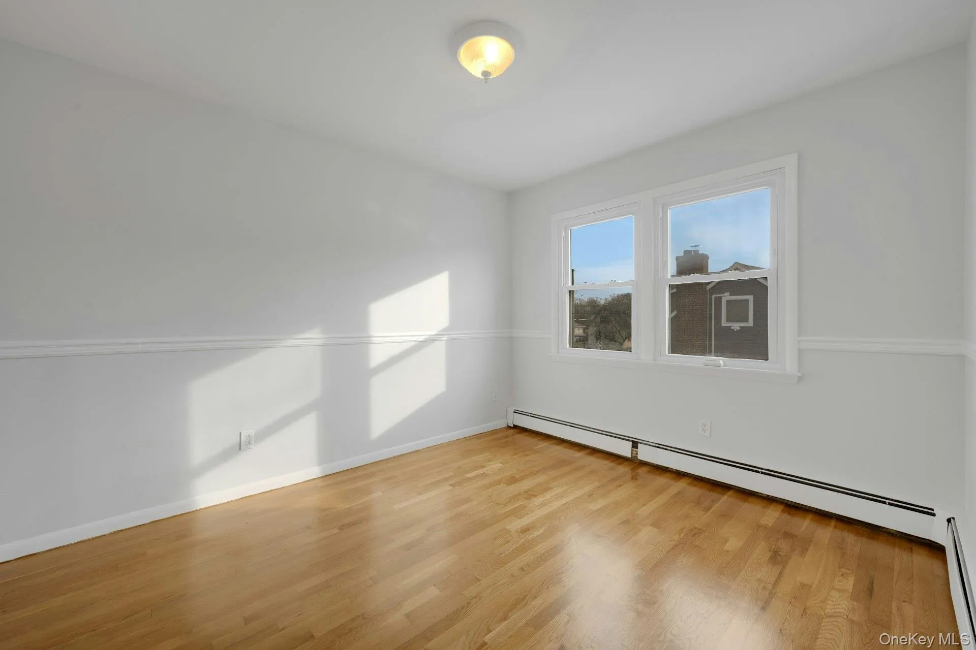 Empty room with baseboard heating and light wood finished floors Empty room with baseboard heating and light wood finished floors