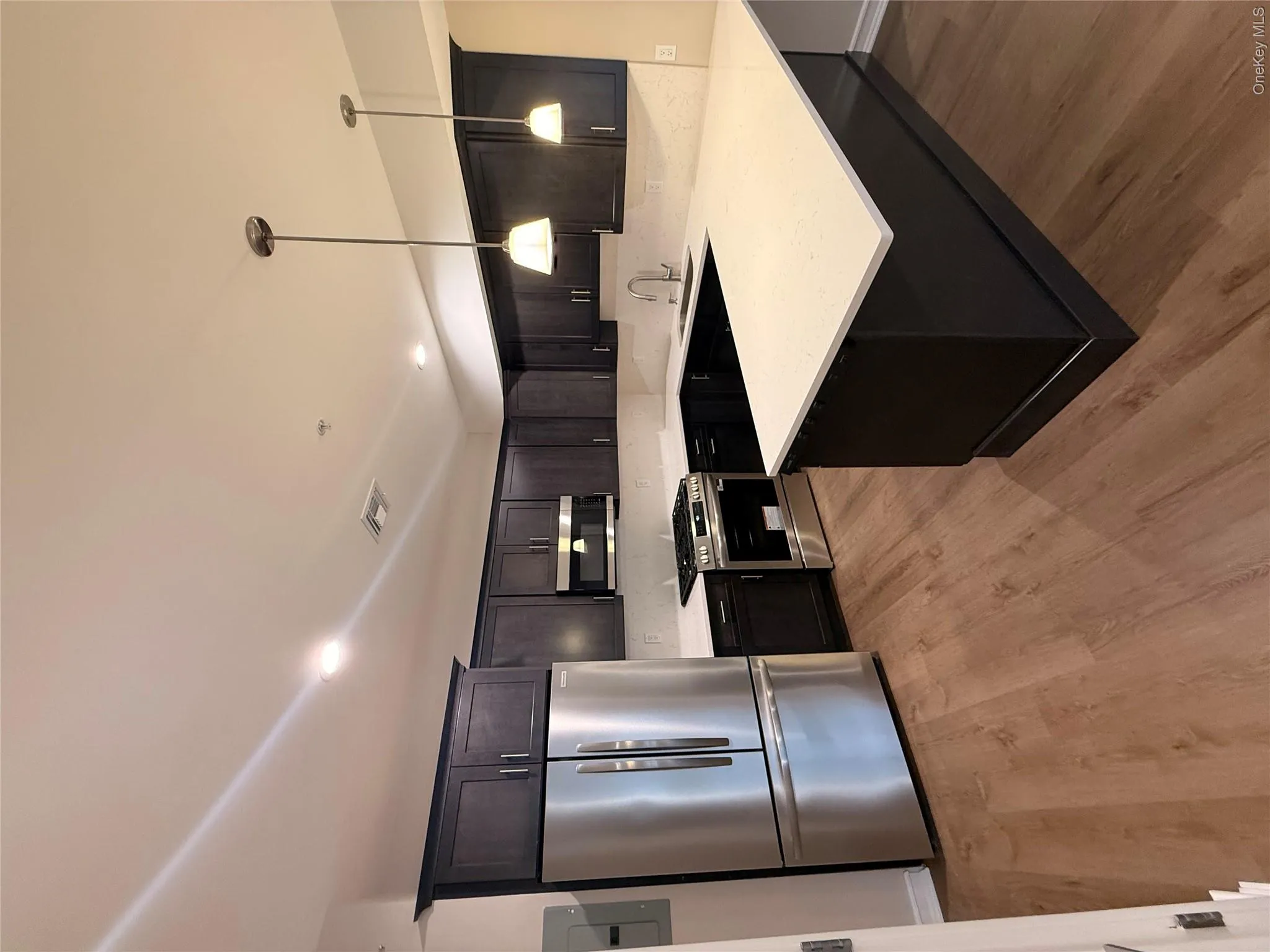 Kitchen with refrigerator, a peninsula, stainless steel range, decorative light fixtures, and a kitchen bar Kitchen with refrigerator, a peninsula, stainless steel range, decorative light fixtures, and a kitchen bar