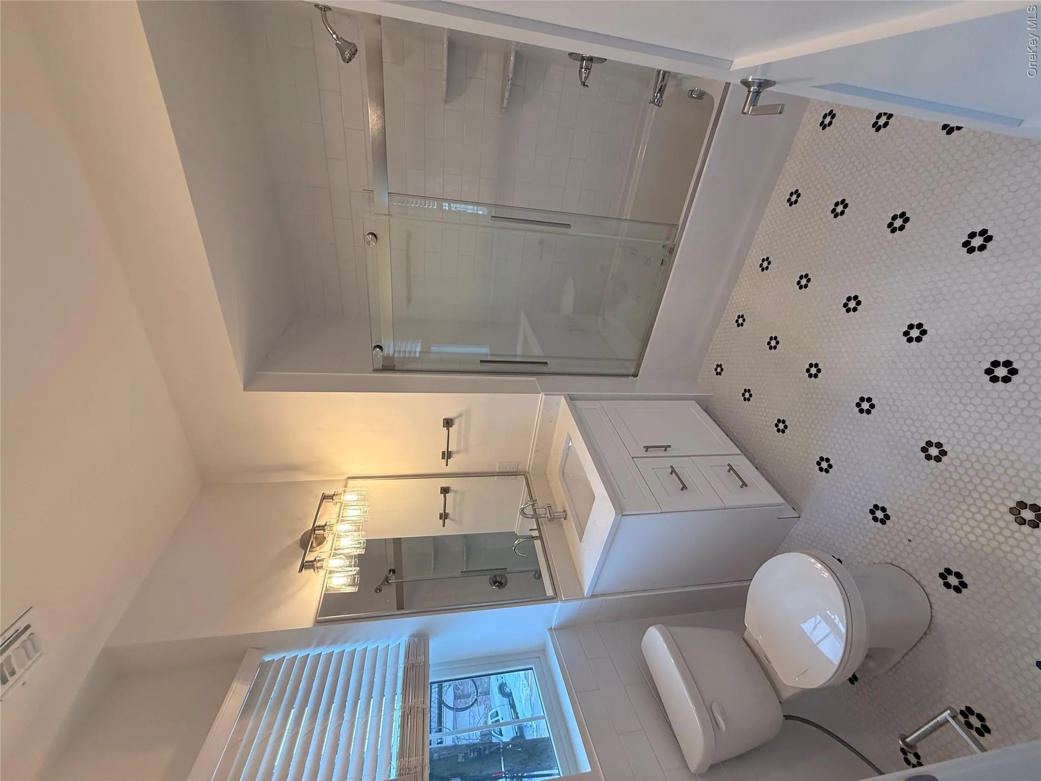 Full bath featuring vanity, shower / bath combination with glass door, tile walls, and wainscoting Full bath featuring vanity, shower / bath combination with glass door, tile walls, and wainscoting