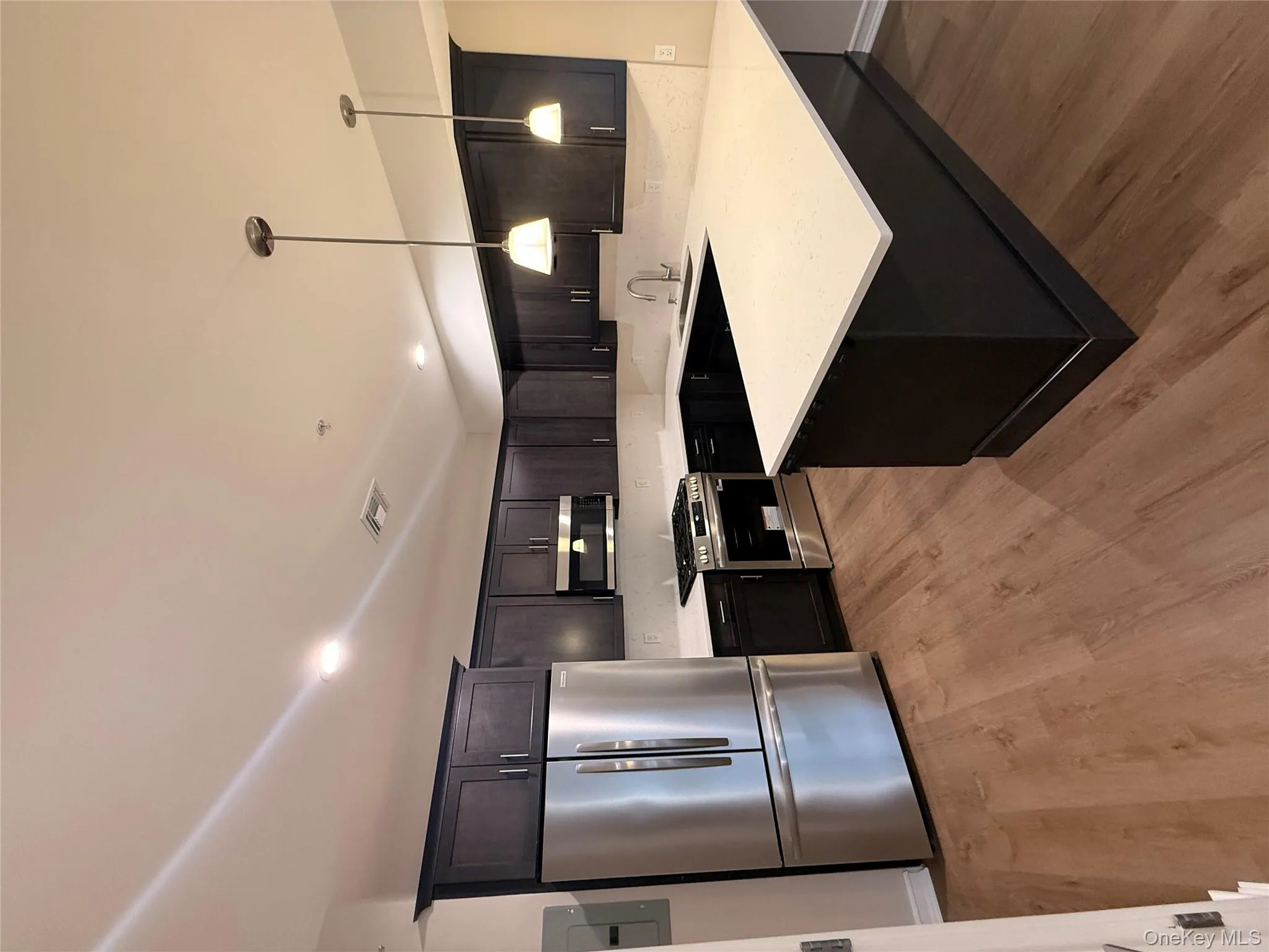 Kitchen with refrigerator, a peninsula, stainless steel range, decorative light fixtures, and a kitchen bar Kitchen with refrigerator, a peninsula, stainless steel range, decorative light fixtures, and a kitchen bar