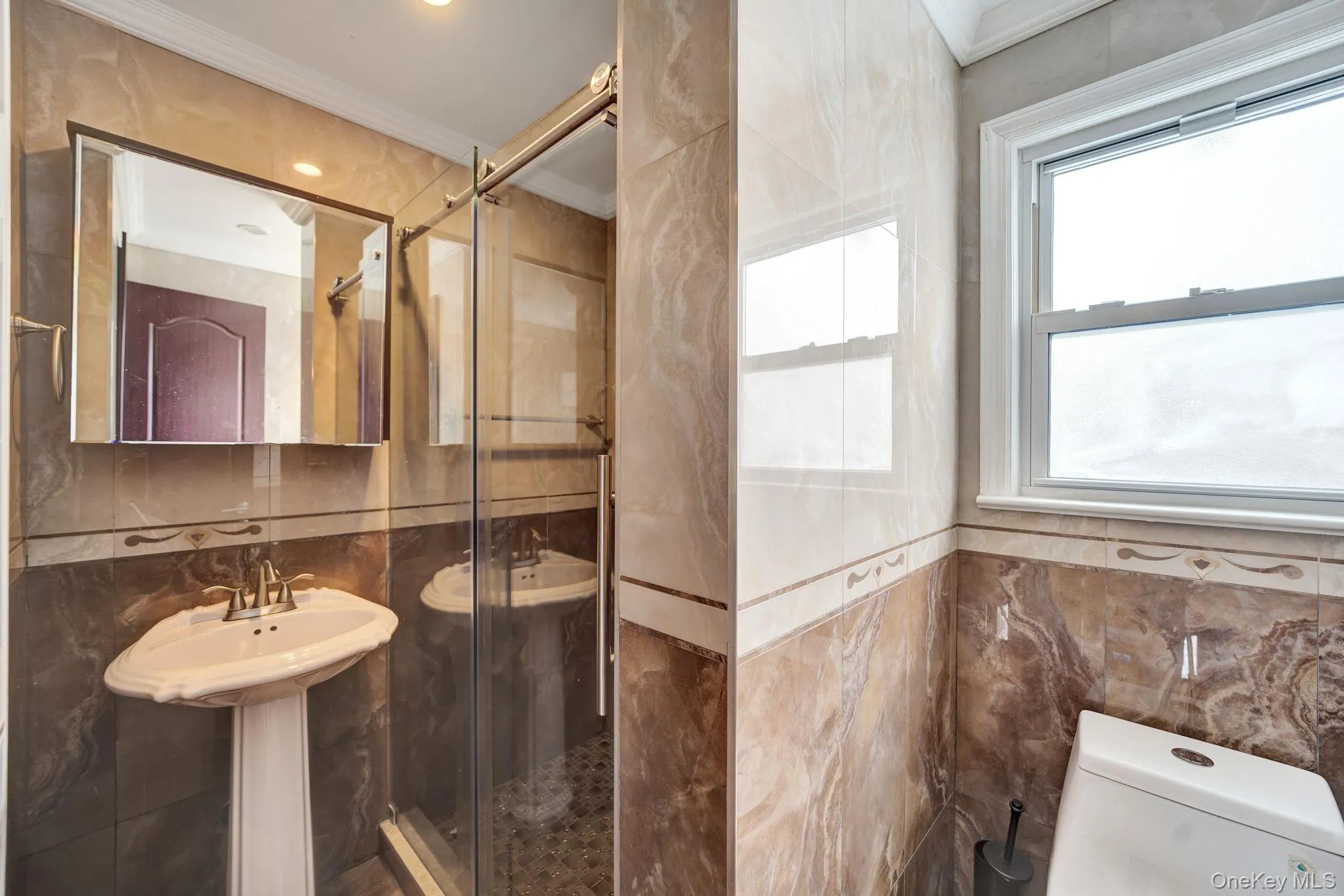 Full bath featuring tile walls, a stall shower, and crown molding Full bath featuring tile walls, a stall shower, and crown molding