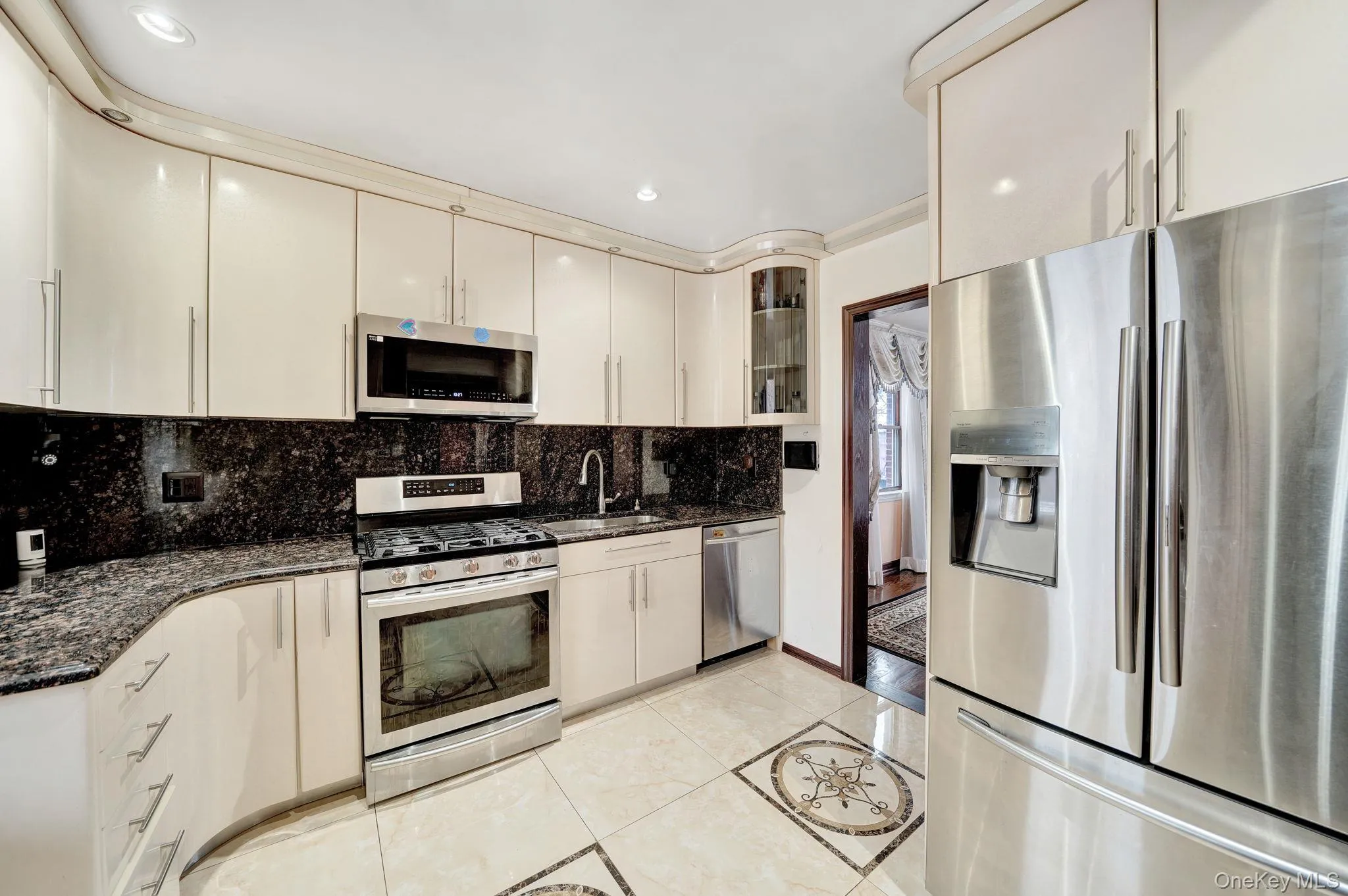 Kitchen featuring stainless steel appliances, dark stone counters, glass insert cabinets, light tile patterned floors, and decorative backsplash Kitchen featuring stainless steel appliances, dark stone counters, glass insert cabinets, light tile patterned floors, and decorative backsplash